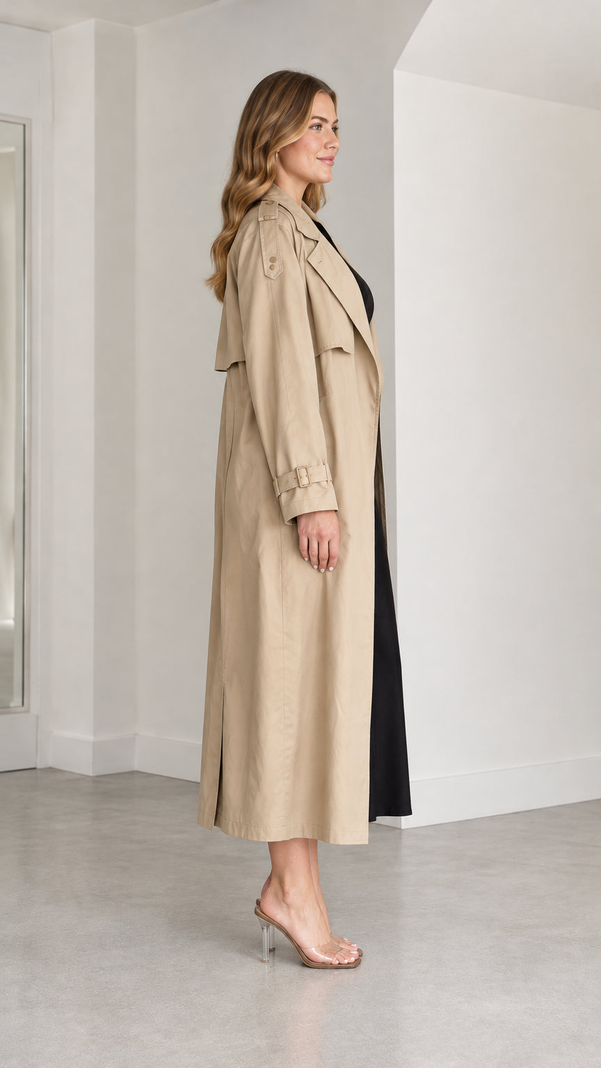 Side profile view of woman wearing khaki long trench coat with open front
