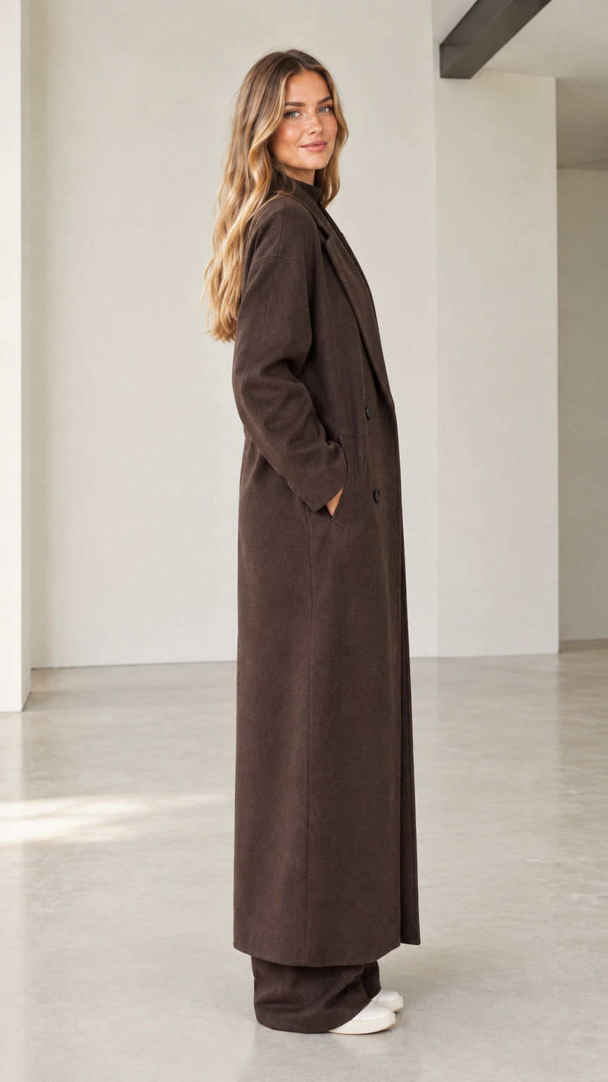 Side profile view of woman modeling full-length dark brown overcoat