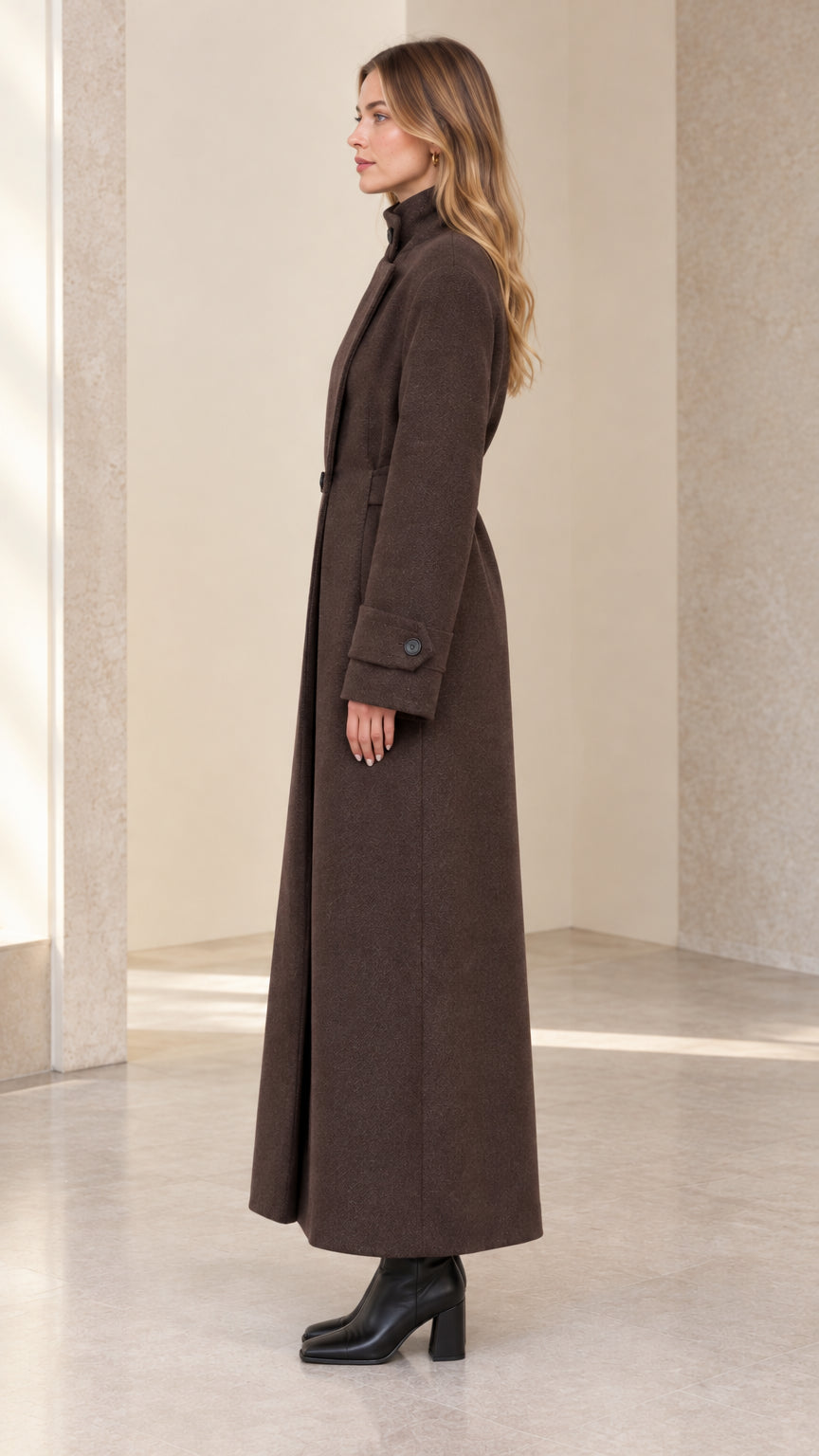 Side profile view of model wearing brown longline tailored maxi coat with belted waist