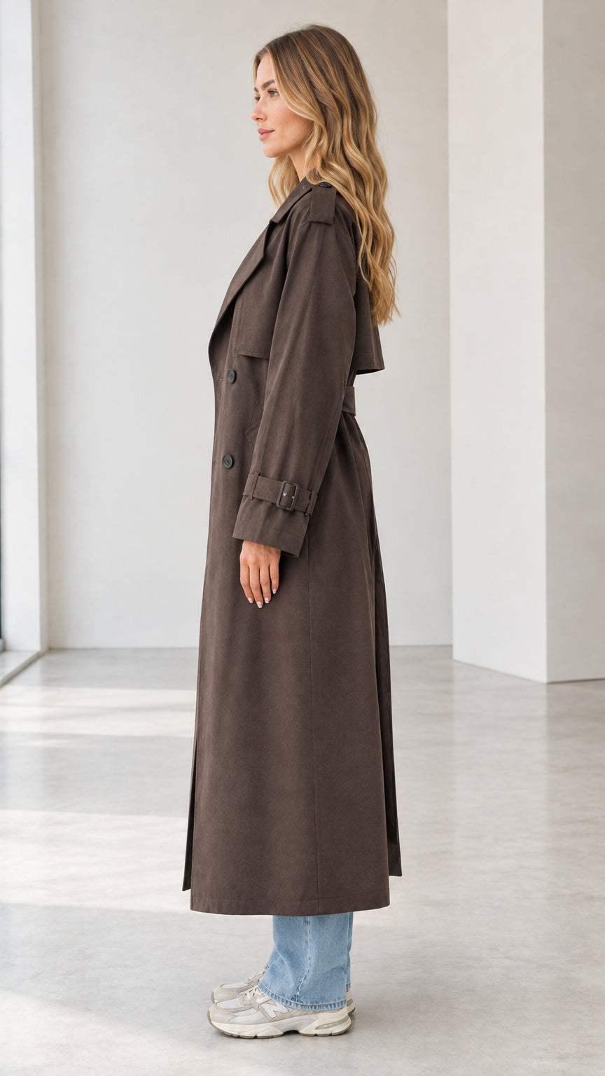 Side profile of woman modeling the full-length dark brown trench coat