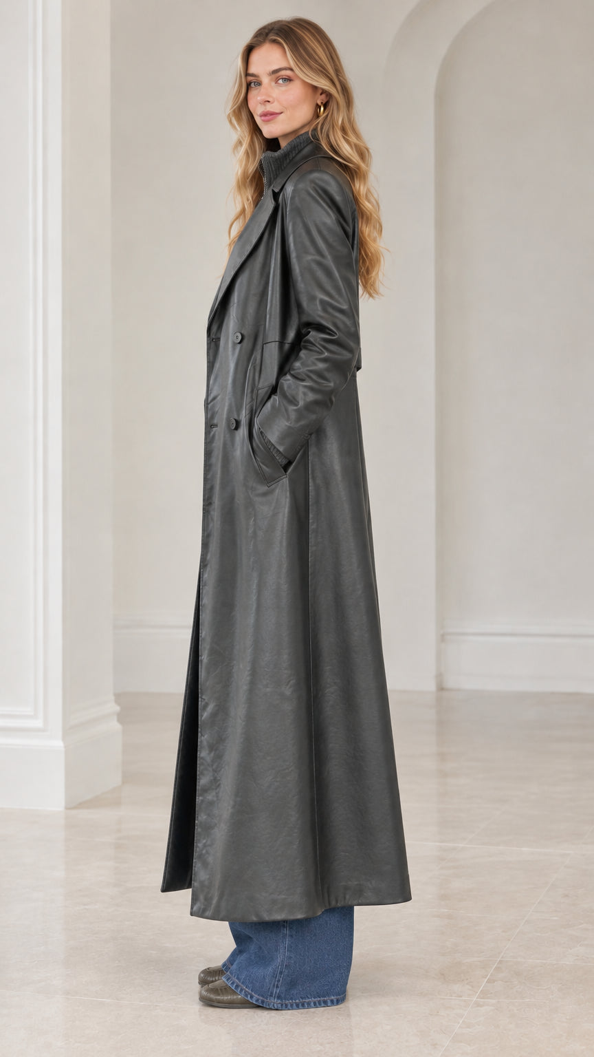 Side profile view of model showcasing the sweeping length and drape of charcoal grey faux leather maxi coat