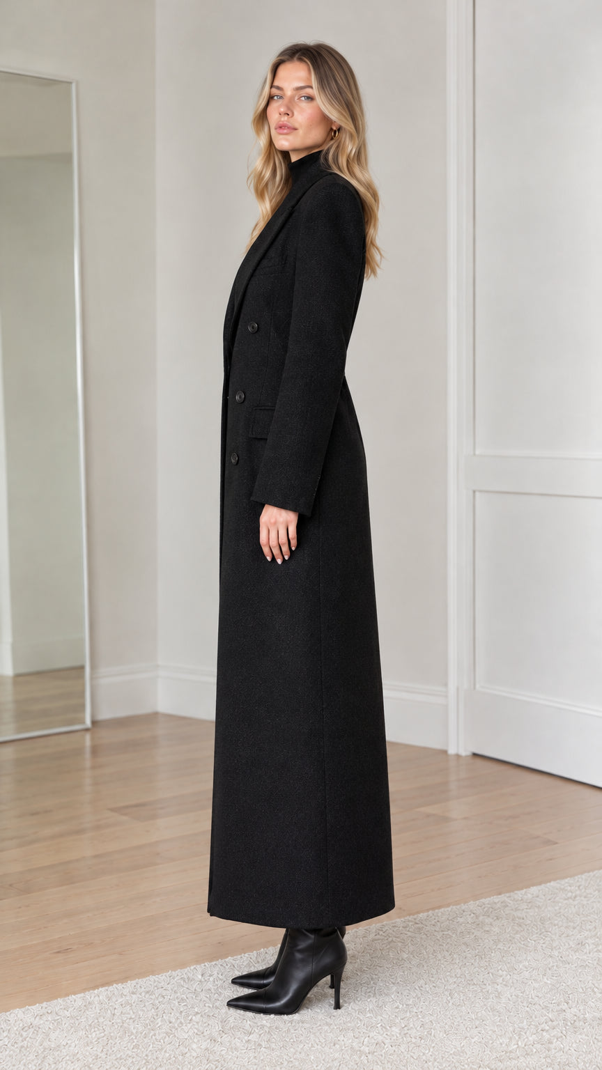 Side profile view of woman modeling black ankle-length tailored overcoat