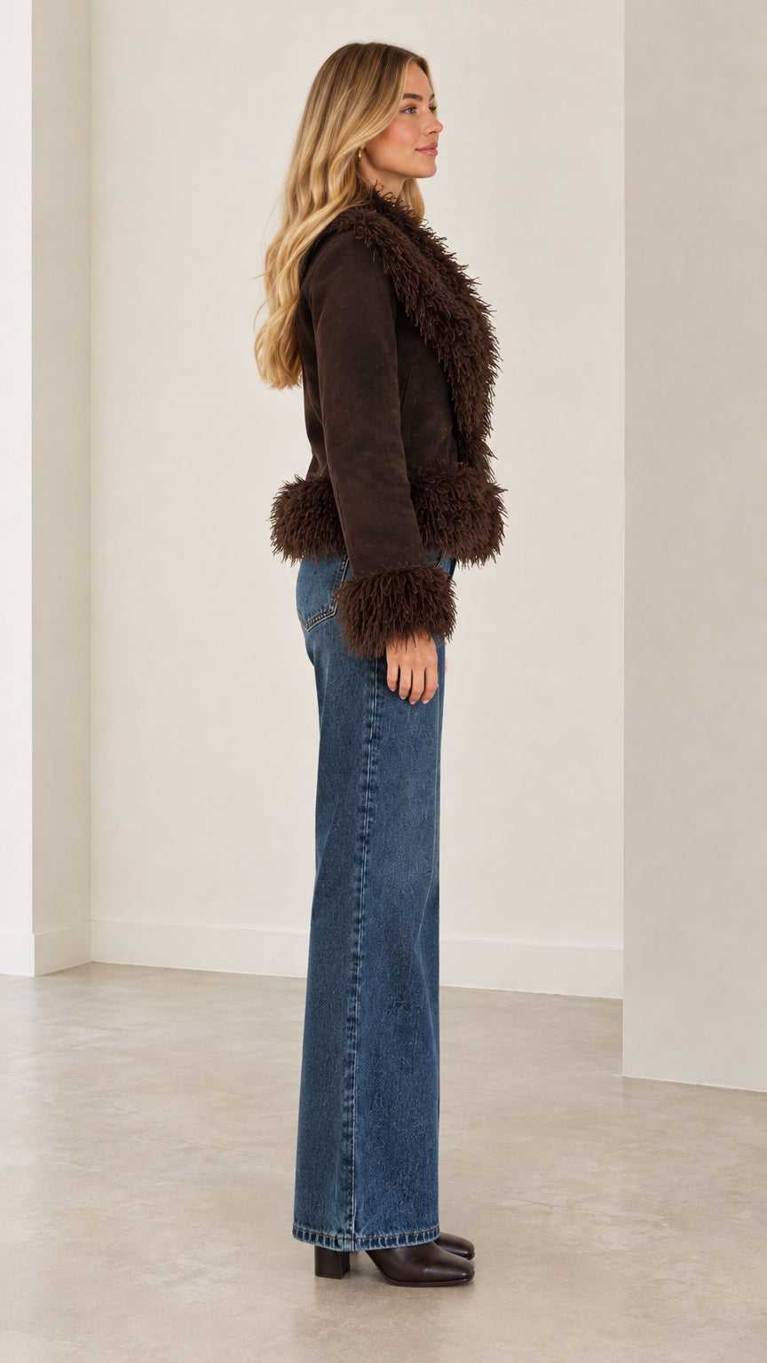 Side profile view of the brown faux suede jacket showing the plush sleeve cuffs and cropped hem