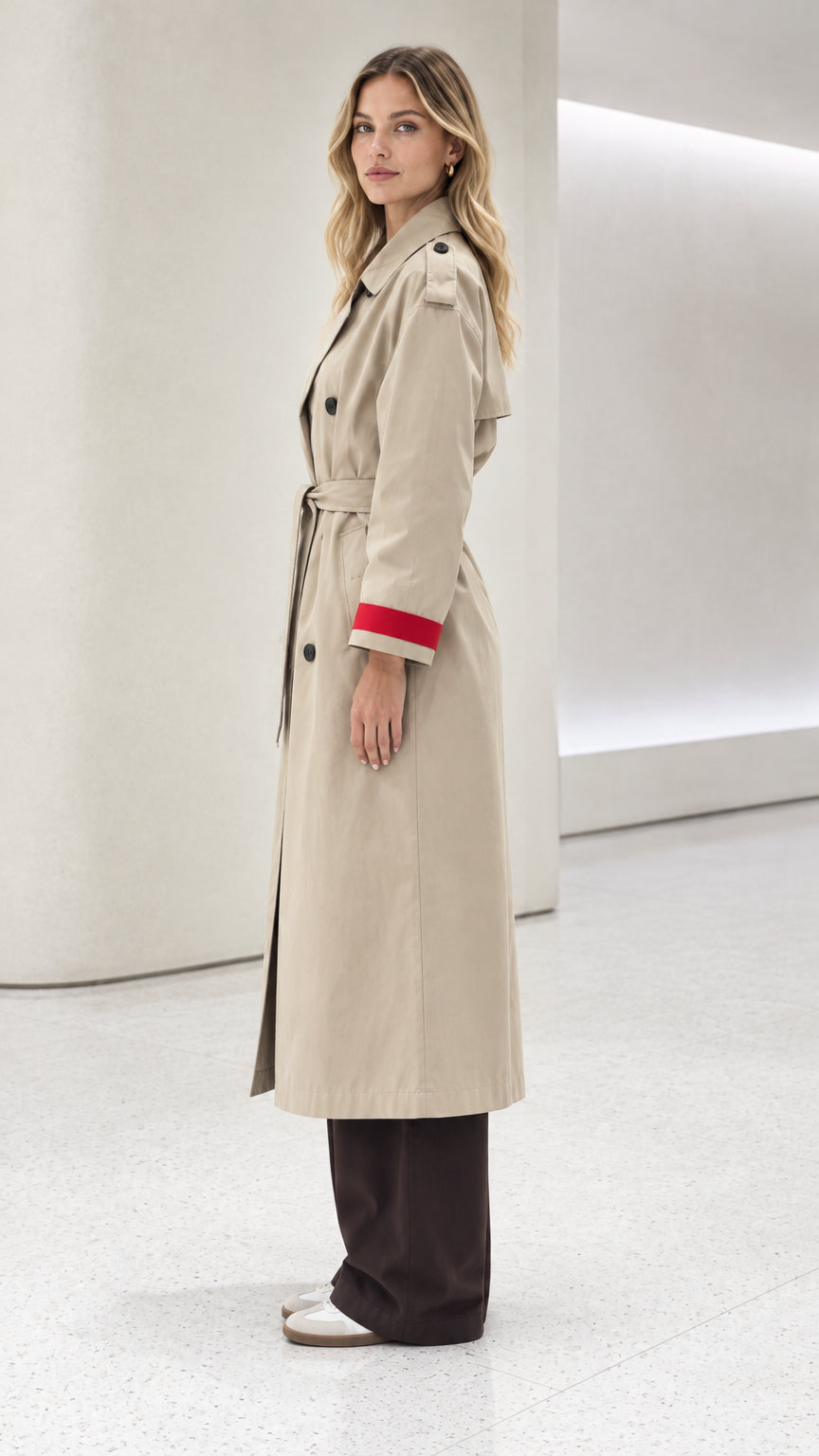 Side profile of model wearing beige long trench coat with contrast cuff detail
