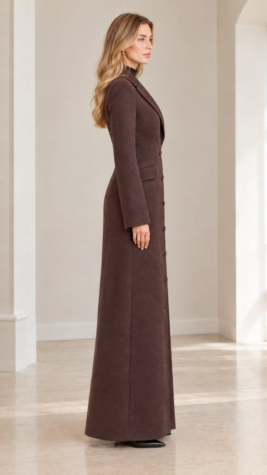 Side profile view of woman wearing brown floor-length tailored coat
