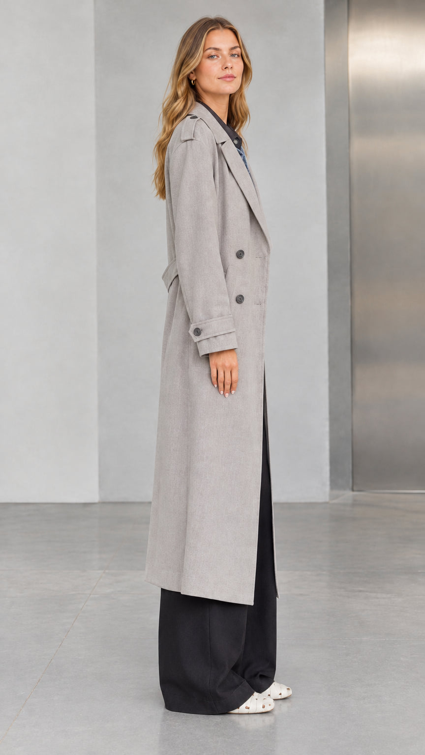 Side profile view of woman wearing Light Grey maxi trench coat showing sleeve cuffs and tailored drape