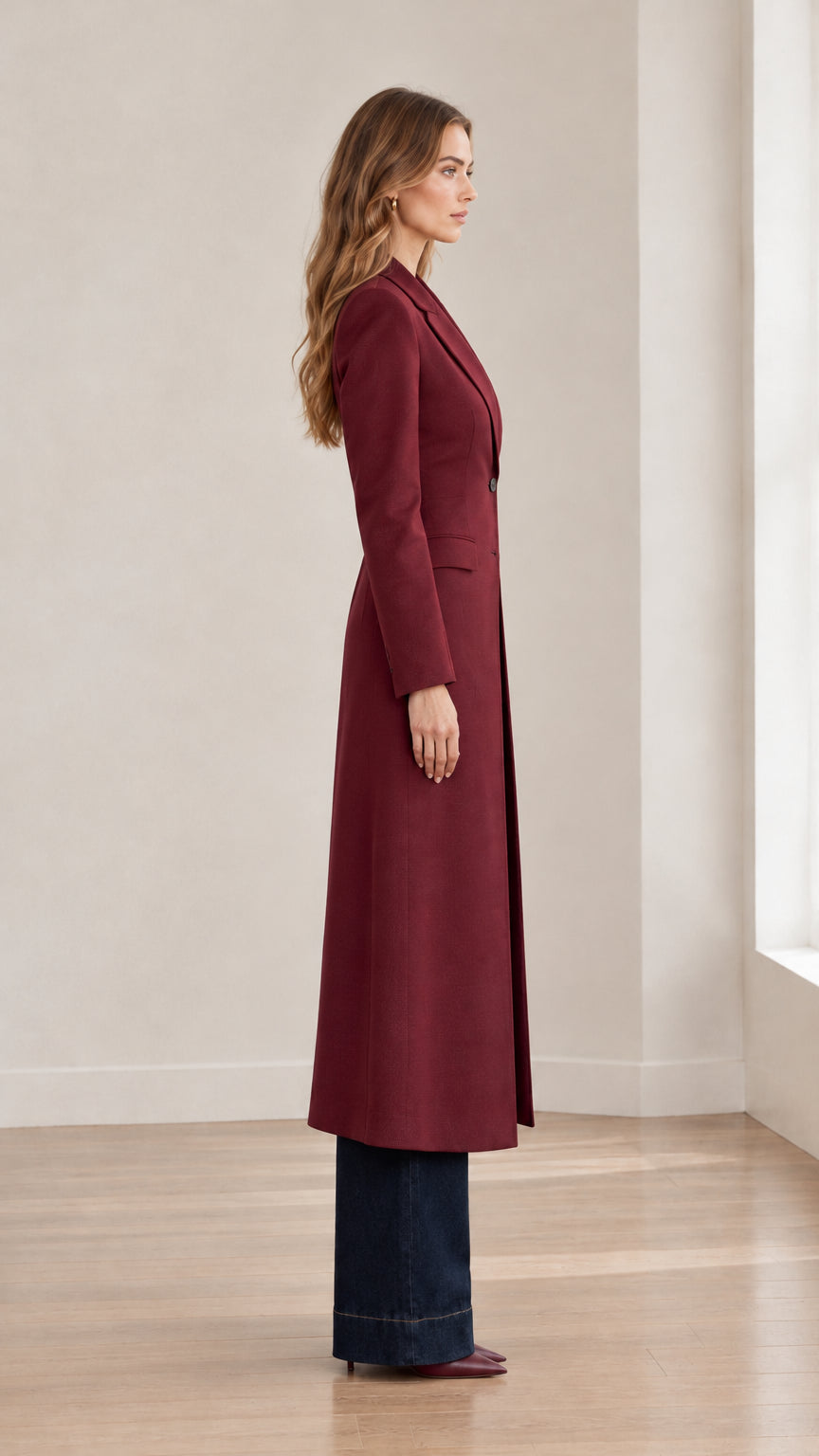Side profile of burgundy longline blazer coat showing structured fit and maxi length