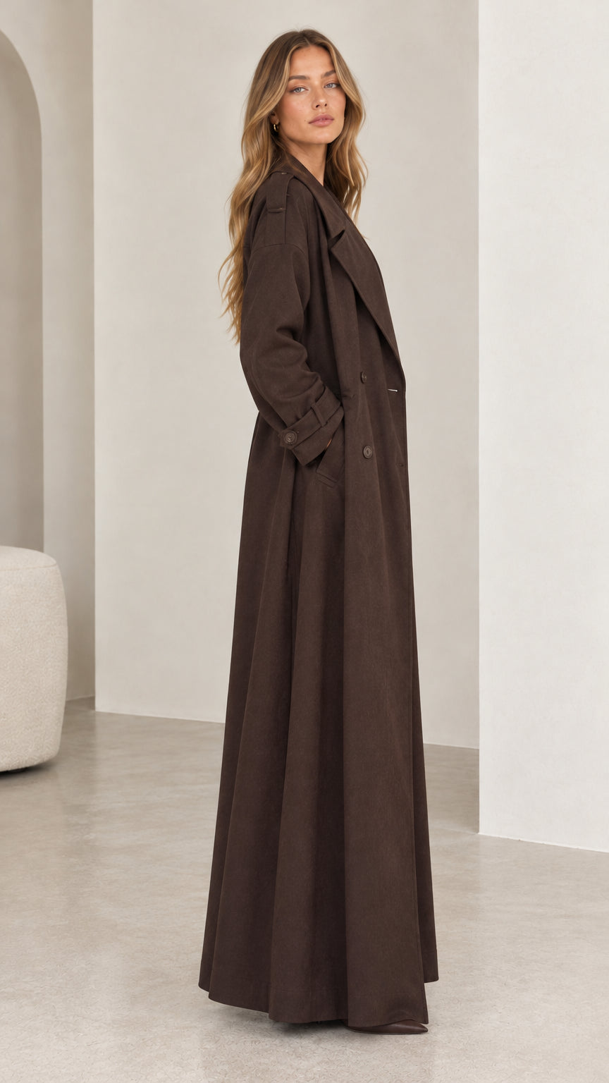 Side profile view of model wearing the long brown maxi trench coat