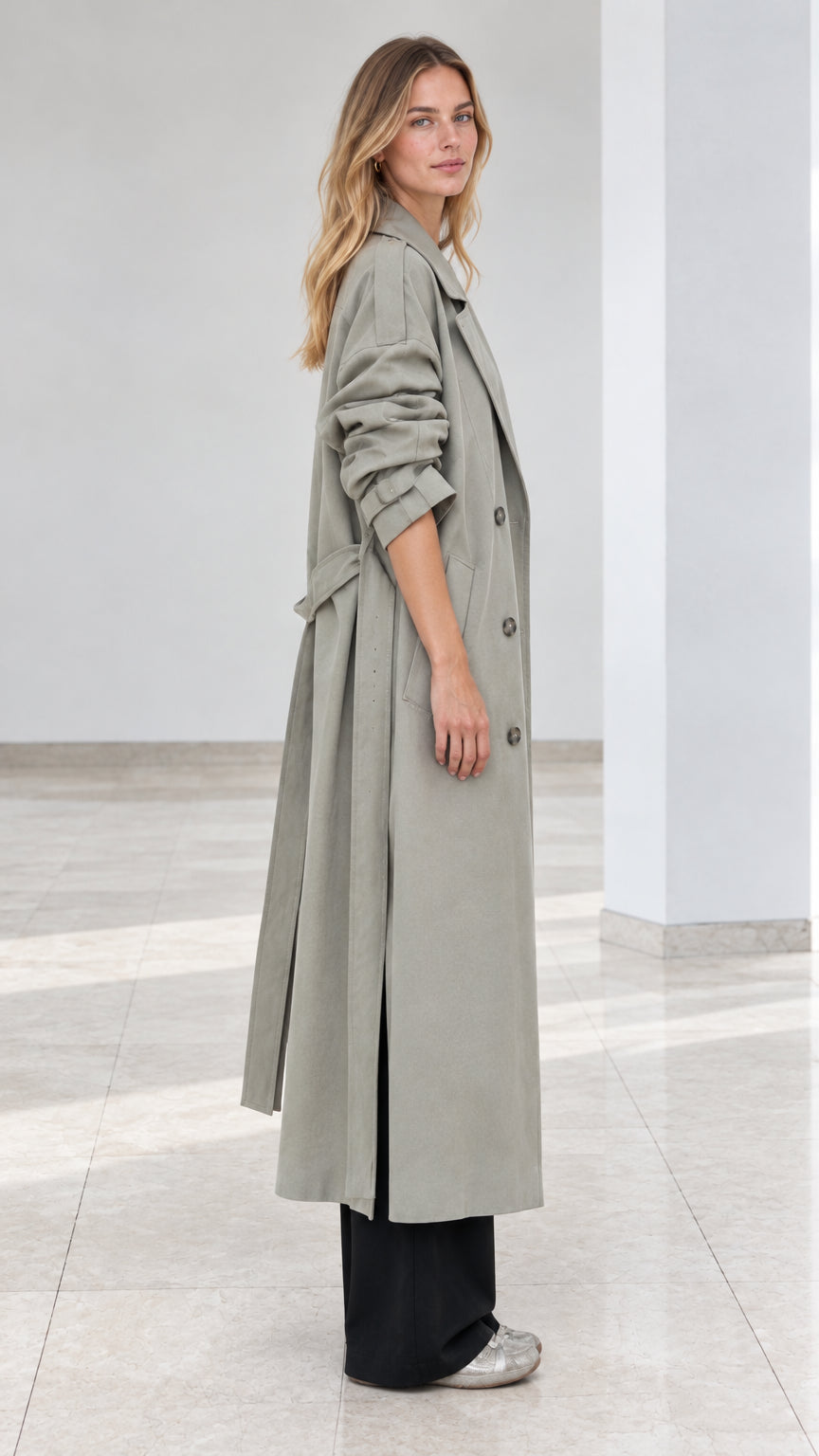 Side profile view of model wearing sage green long trench coat