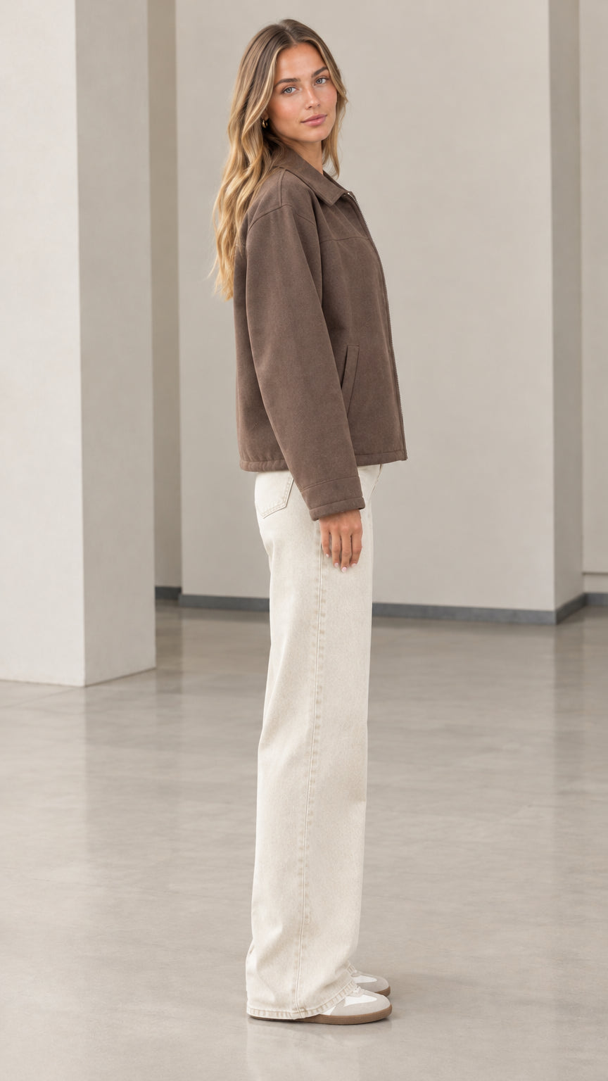 Side profile view of model wearing the brown zip-up jacket