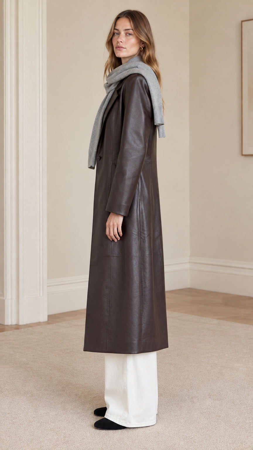 Side profile view of dark brown maxi length faux leather coat showing clean structured tailoring