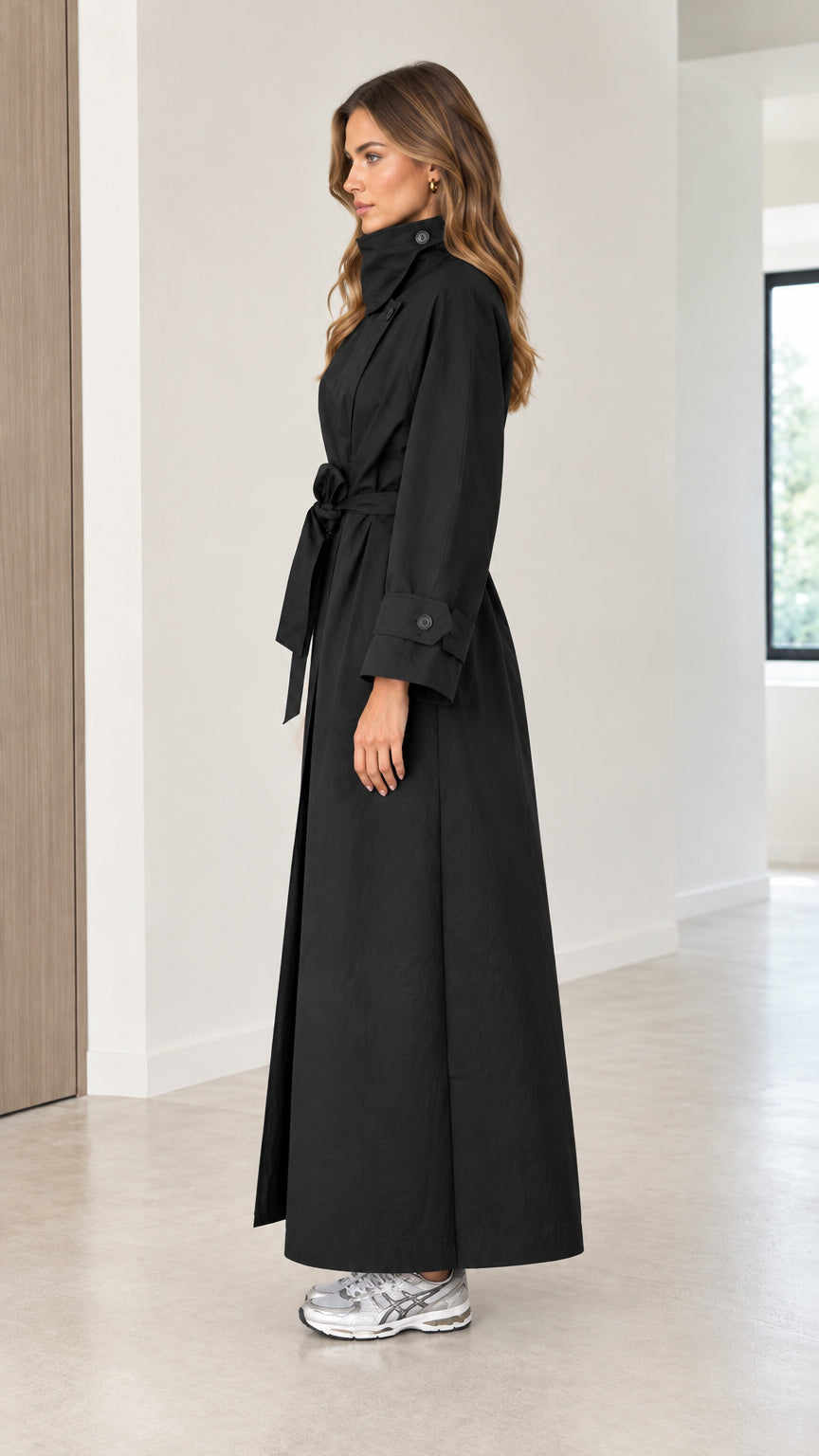 Side profile view of a woman wearing a full-length black trench coat