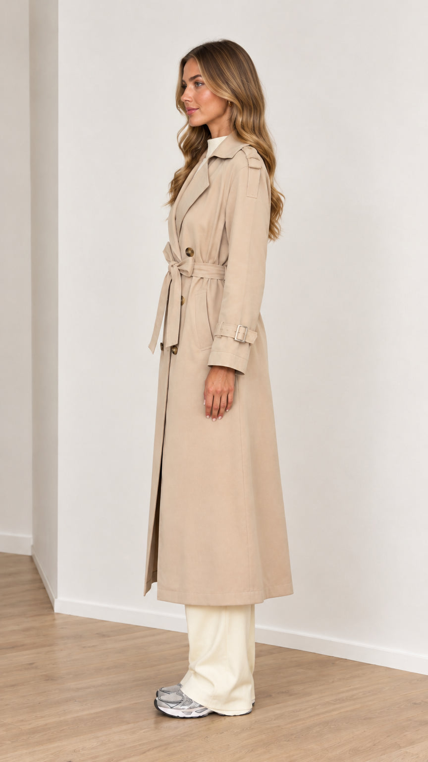 Side profile of a woman wearing a beige longline belted trench coat