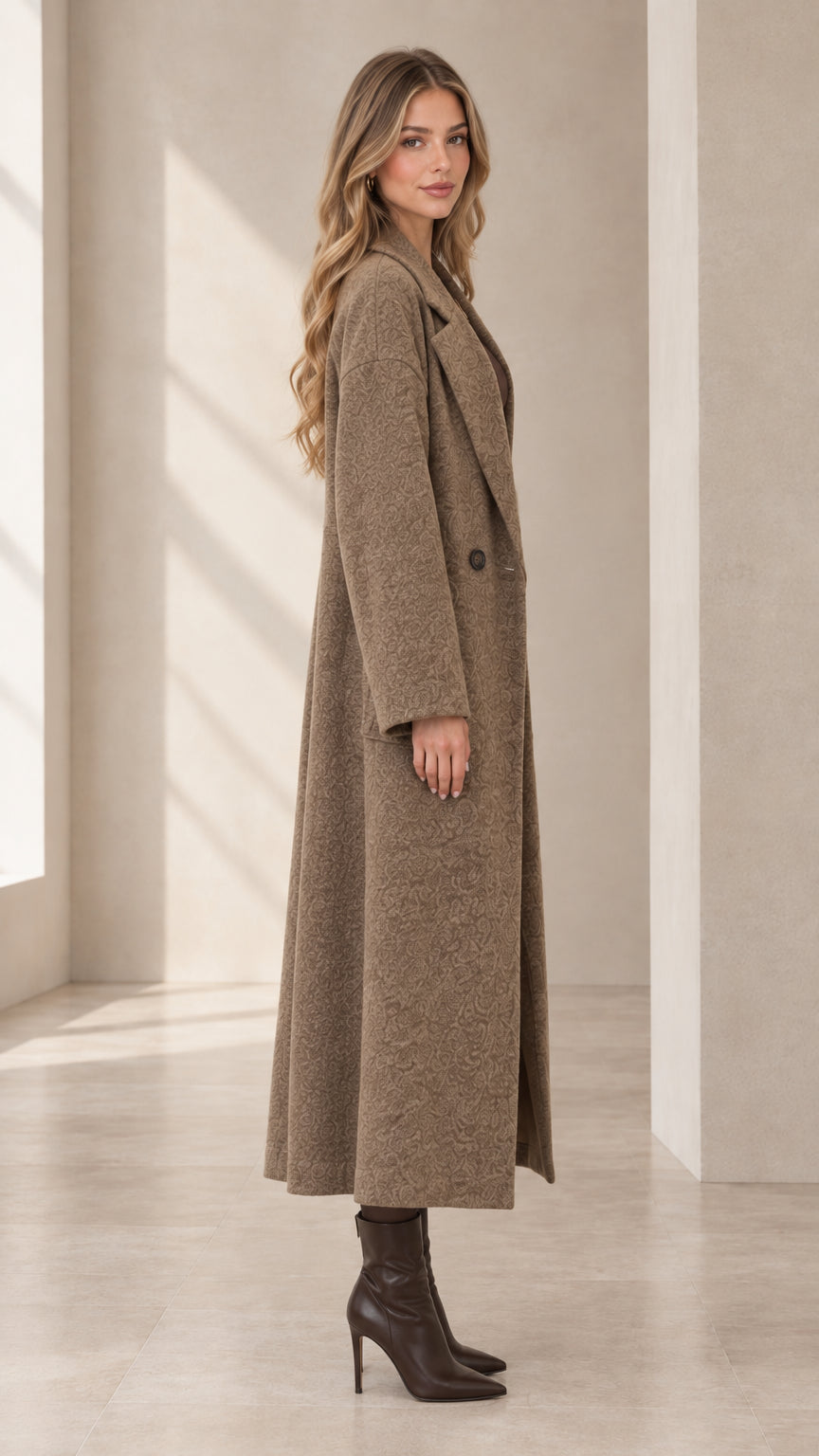 Side profile view of model showcasing the maxi length of the mocha textured overcoat