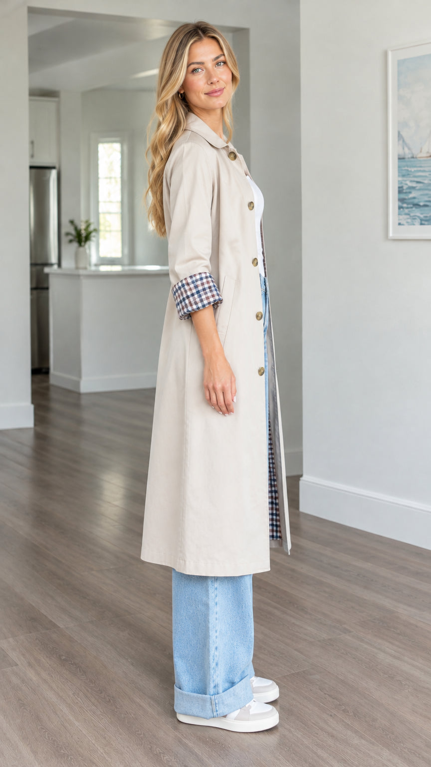 Side angle view of woman wearing beige longline trench coat with turned-up check cuffs