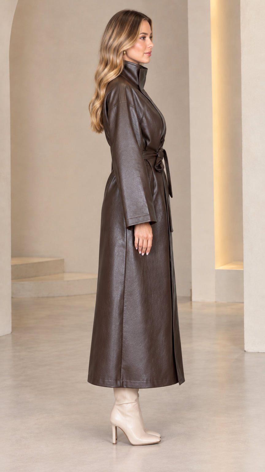 Side profile view of dark brown faux leather belted maxi coat with stand collar