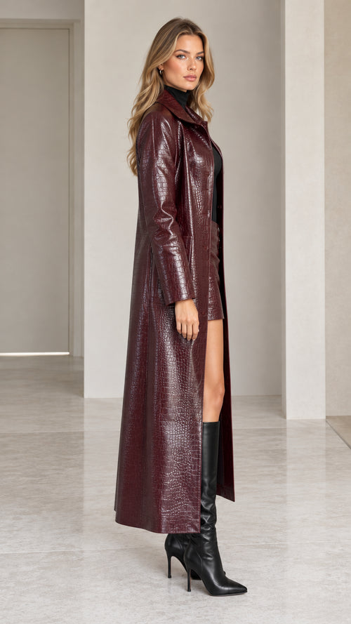 Side angle view of model wearing long burgundy crocodile-embossed faux leather trench coat