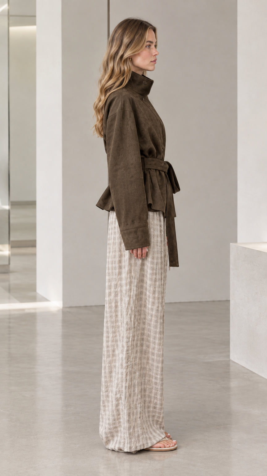 Side profile view of dark olive high-neck belted jacket showing waist tie and collar construction