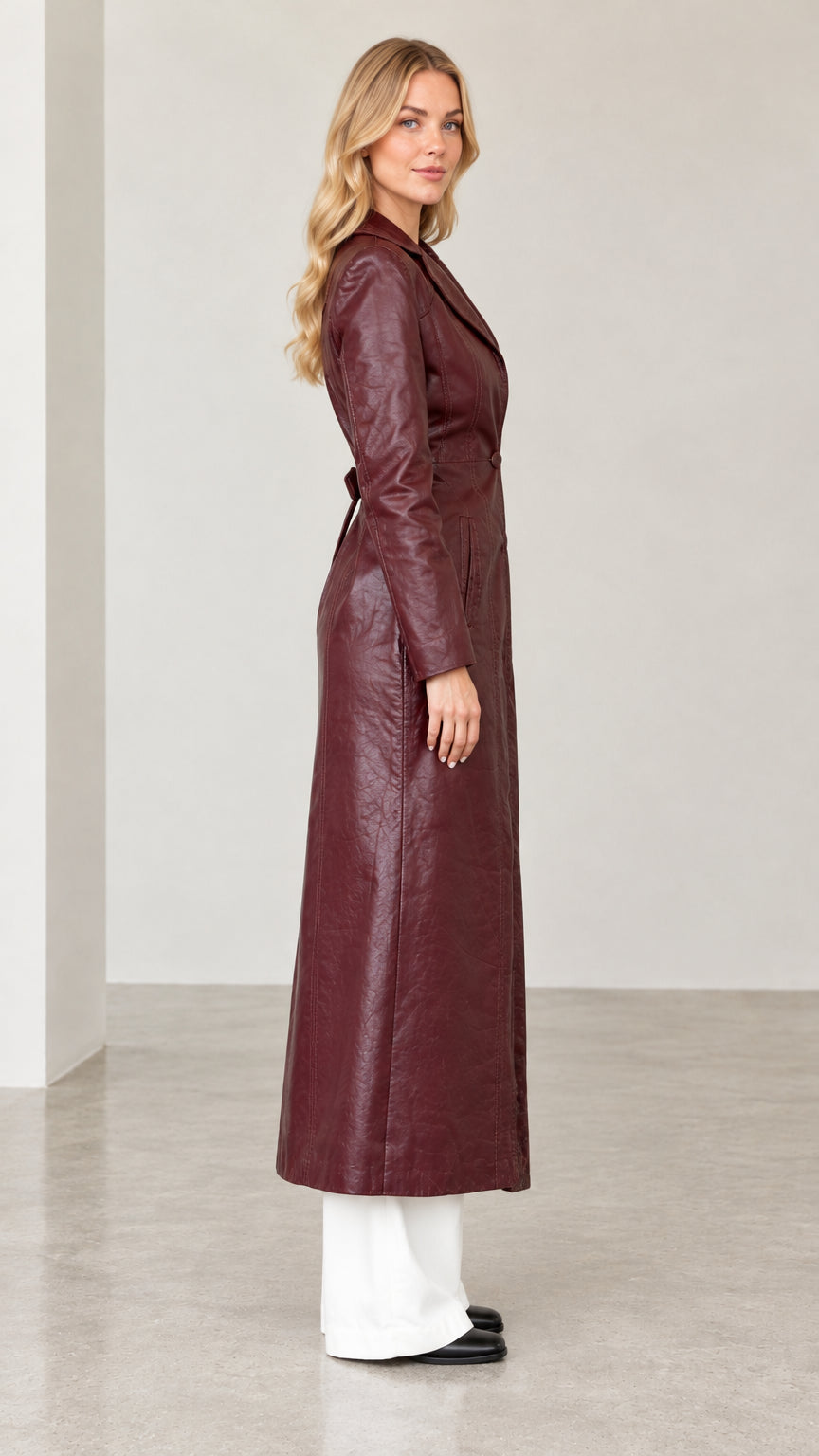 Side profile view of woman modeling longline burgundy leather-look coat