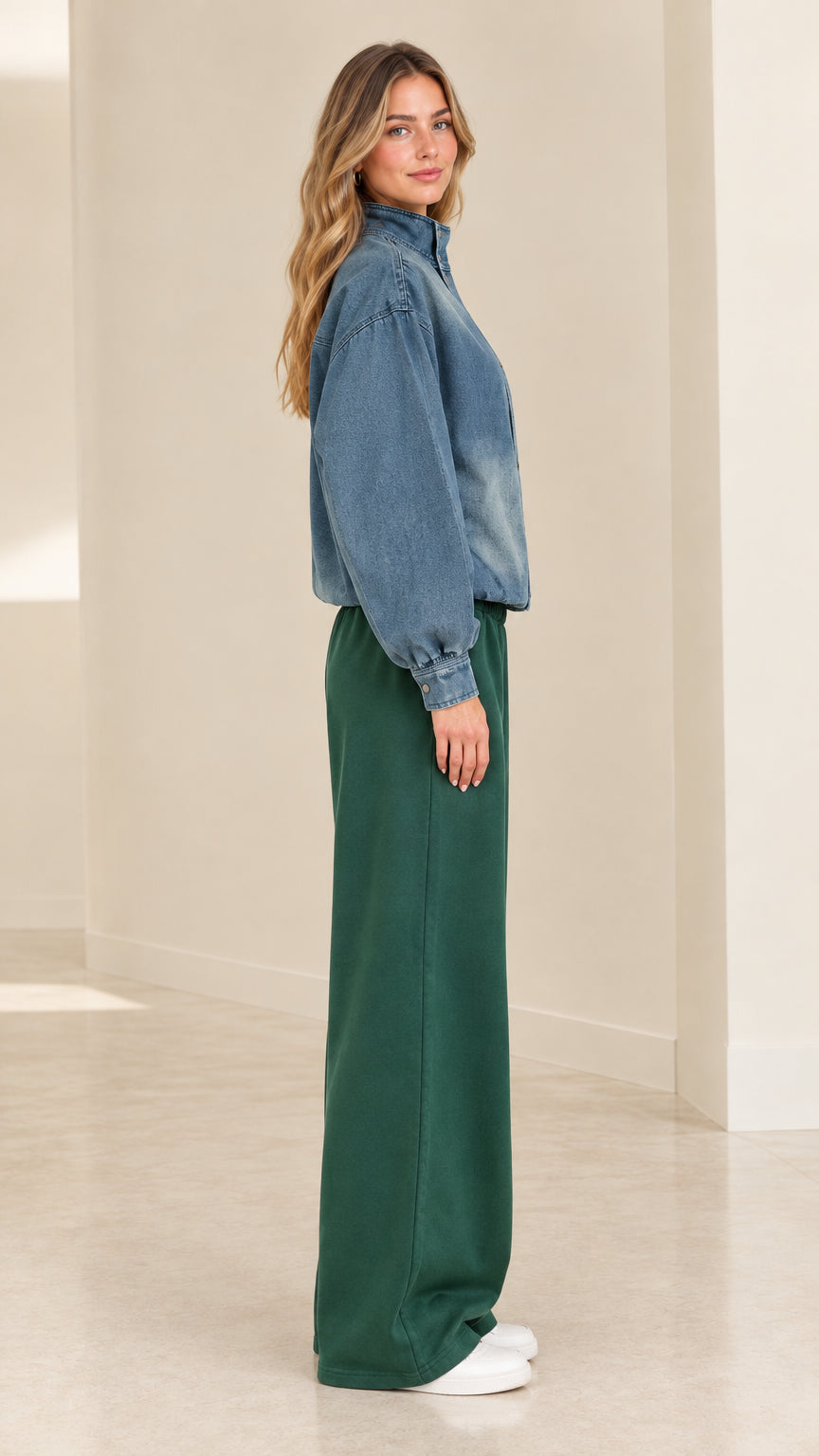 Side profile of model wearing blue washed jacket and green pants