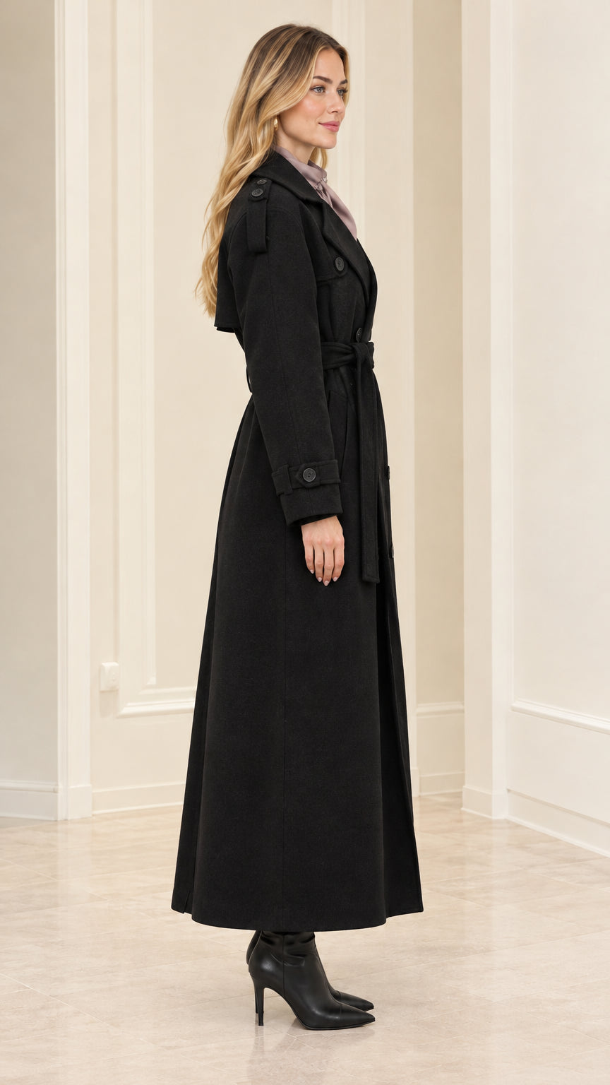 Side profile view of woman wearing Black longline trench coat with heeled boots