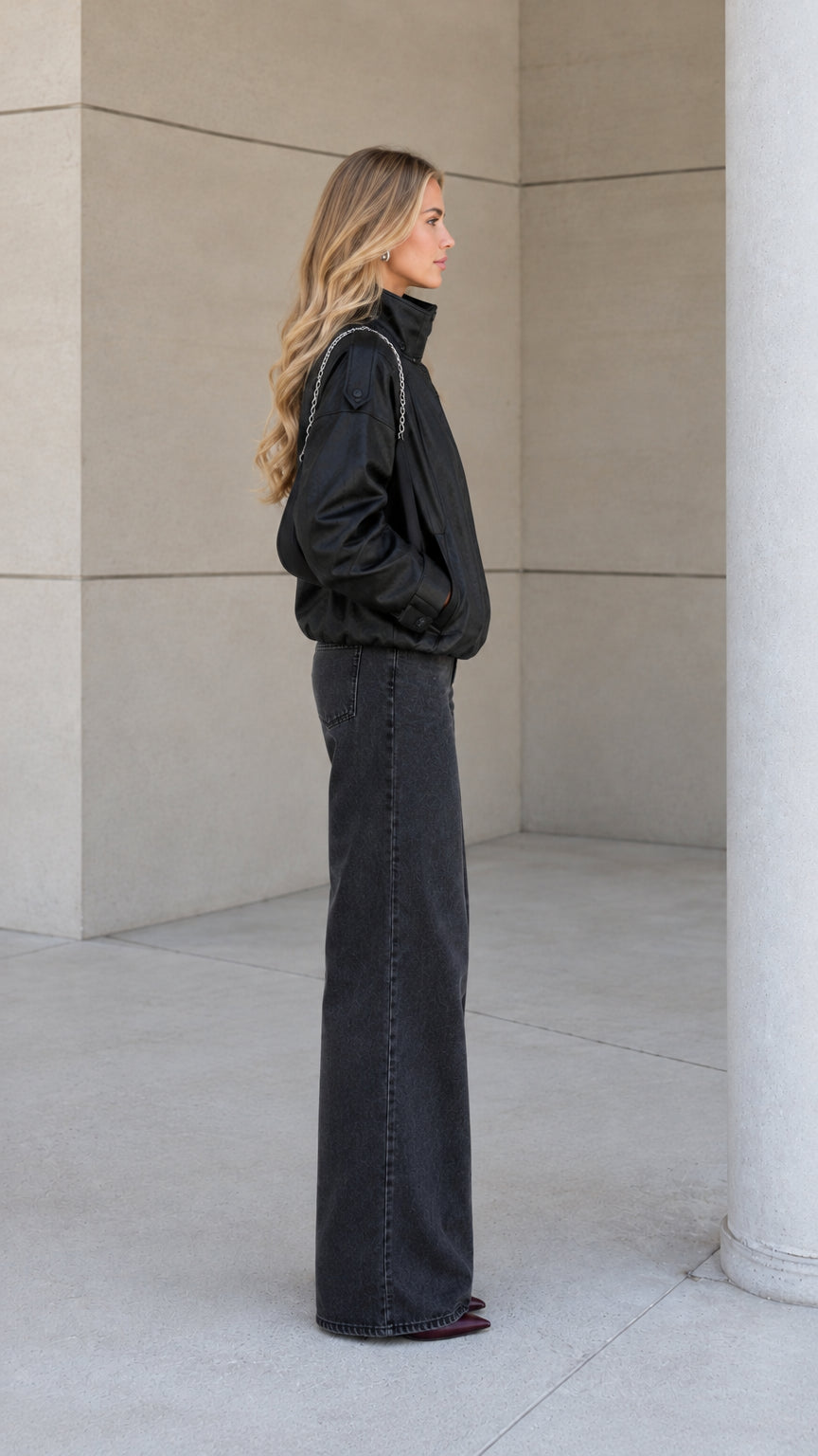 Side profile of model wearing the black high-neck bomber jacket