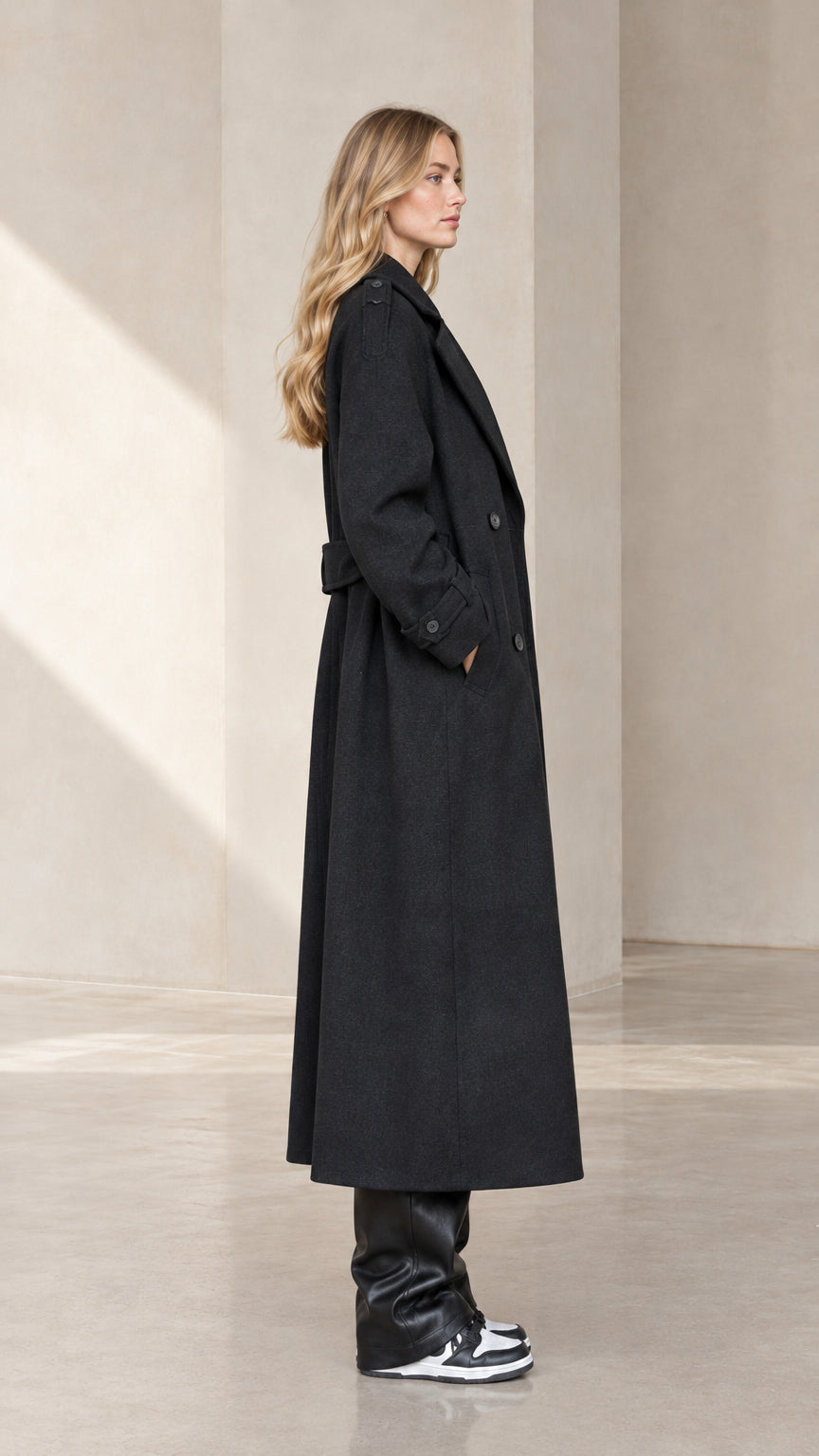 Side profile view of woman wearing Black long tailored overcoat
