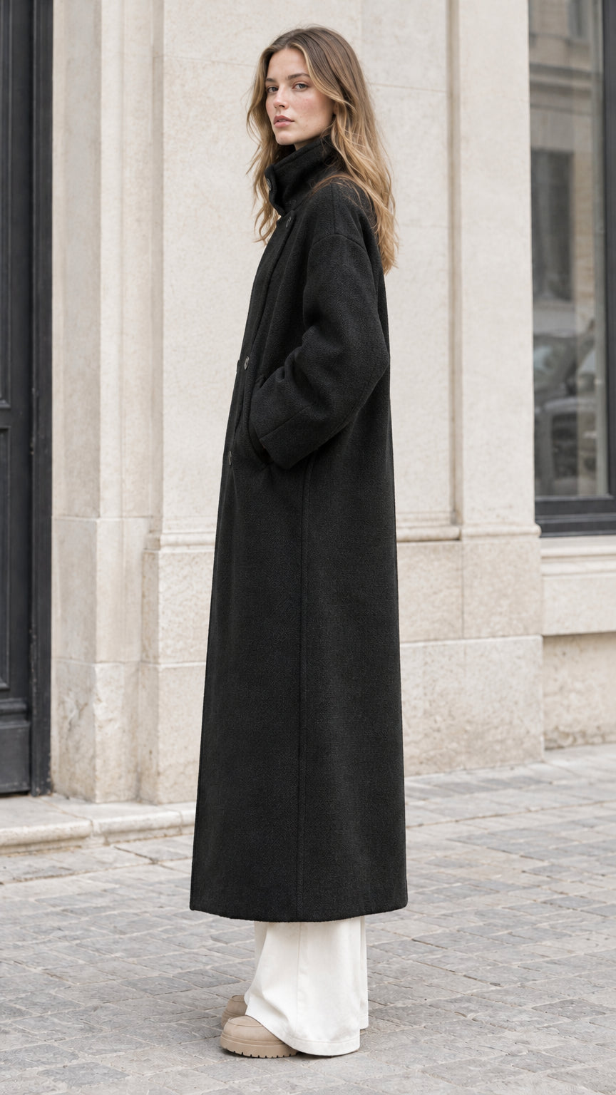 Side profile view of woman wearing Black long relaxed-fit overcoat
