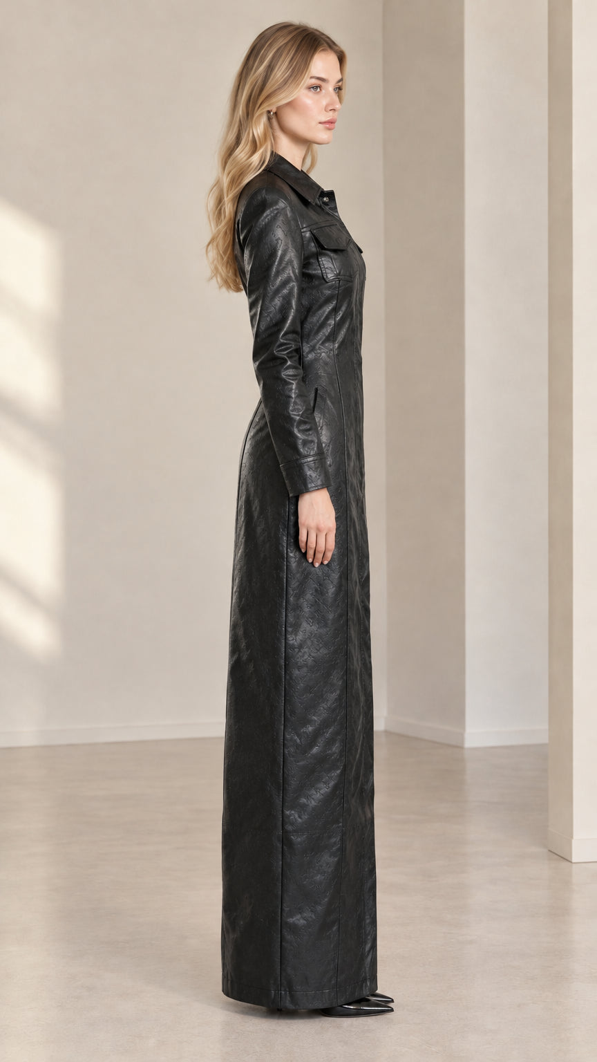 Side profile view of model showcasing tailored silhouette of black faux leather maxi dress