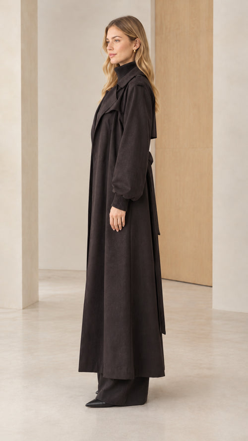 Side profile view of woman modeling black ankle length trench coat