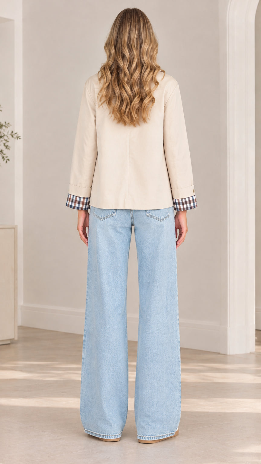 Back full-length view of model wearing beige lightweight shirt jacket with visible plaid cuff accents