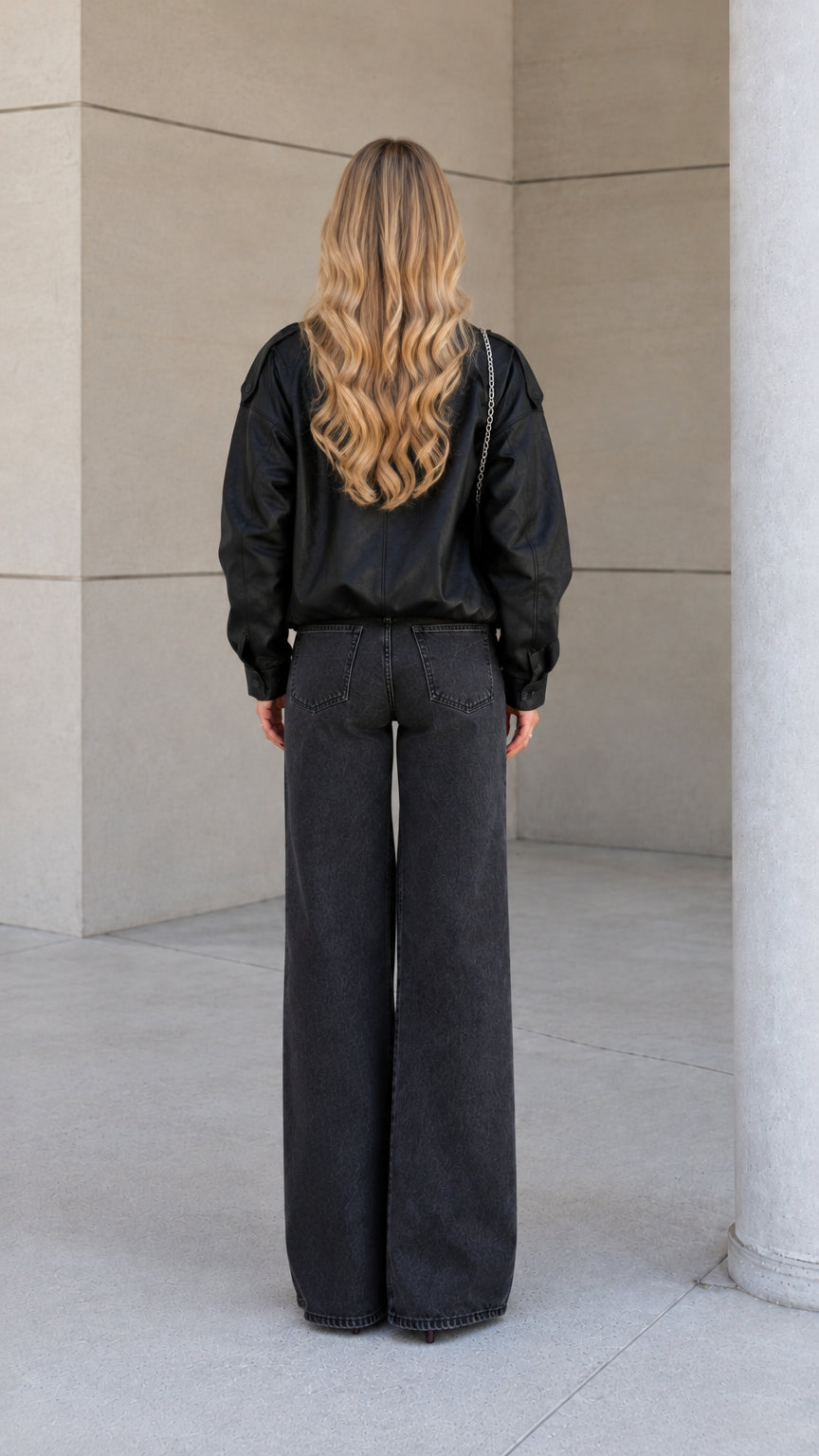 Back view of model wearing the black high-neck bomber jacket