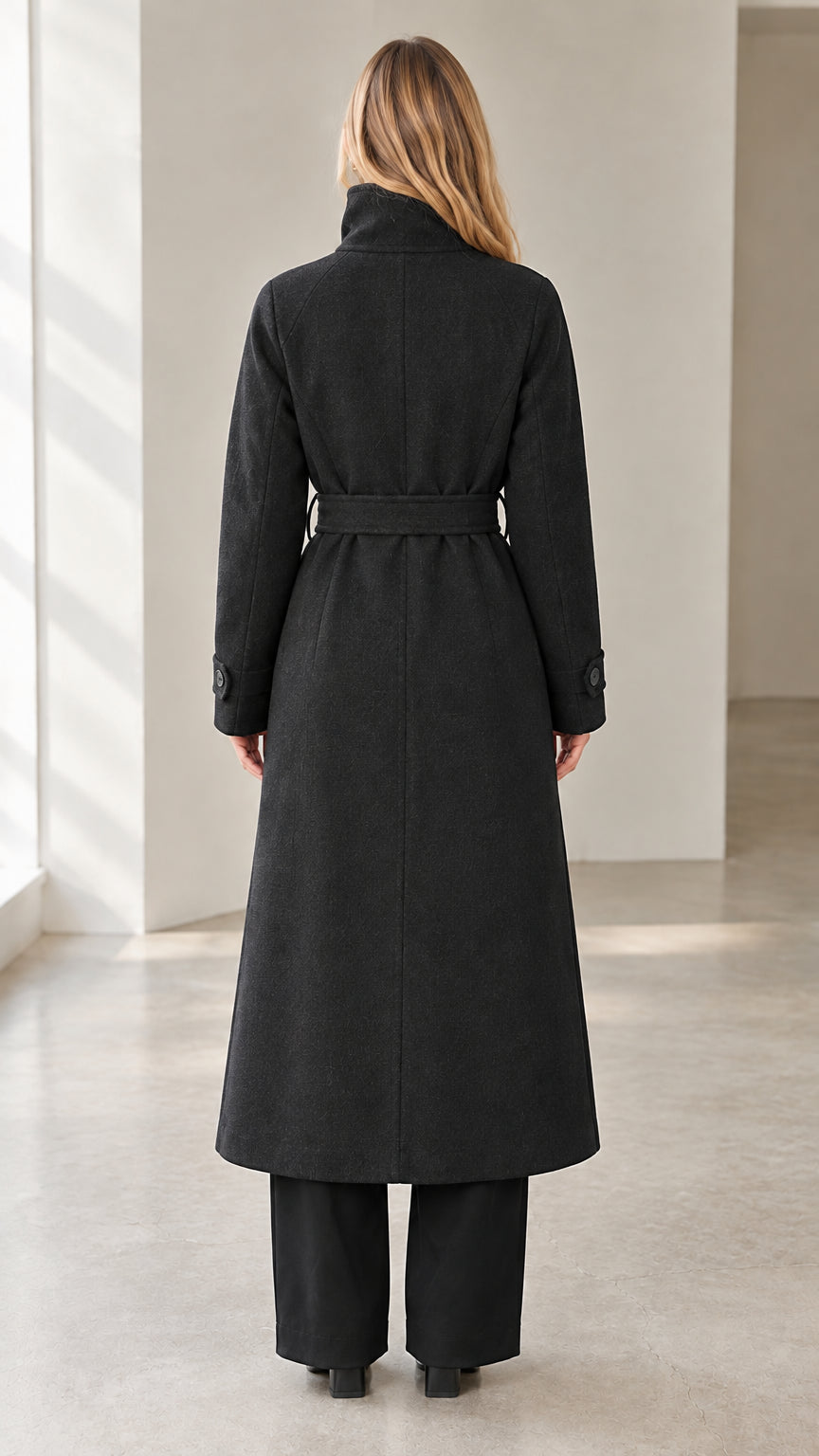 Back view of model showcasing full-length black overcoat with tie belt