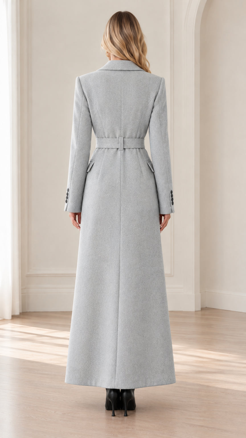 Back view of woman wearing Light Grey floor-length overcoat with waist belt