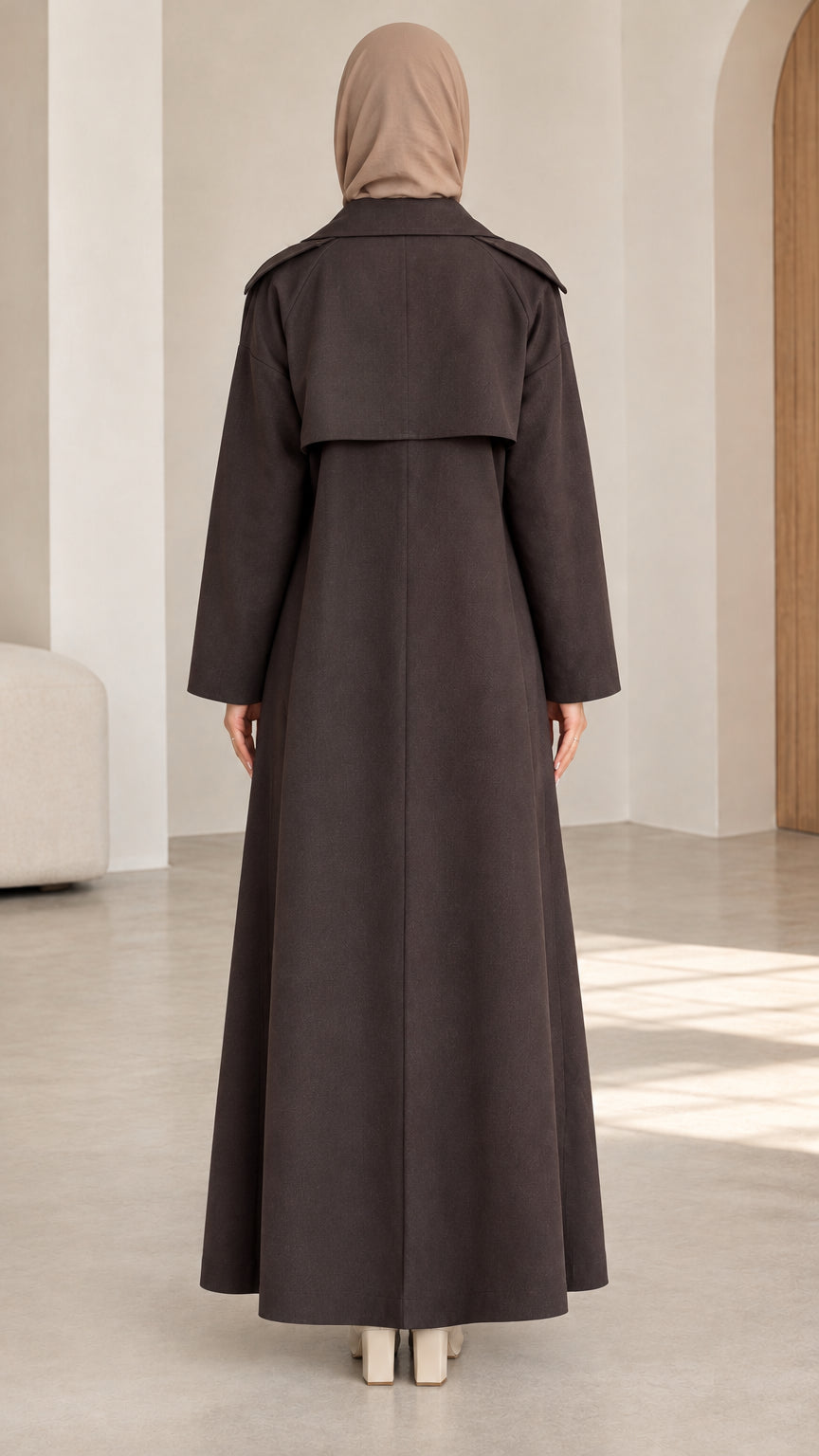 Back view of woman wearing dark brown maxi trench coat showing back storm flap