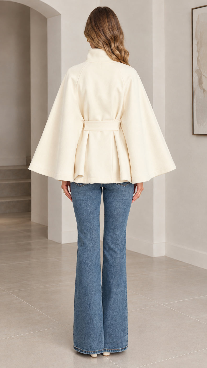 Back view of cream belted cape coat showing waist pleats and drape