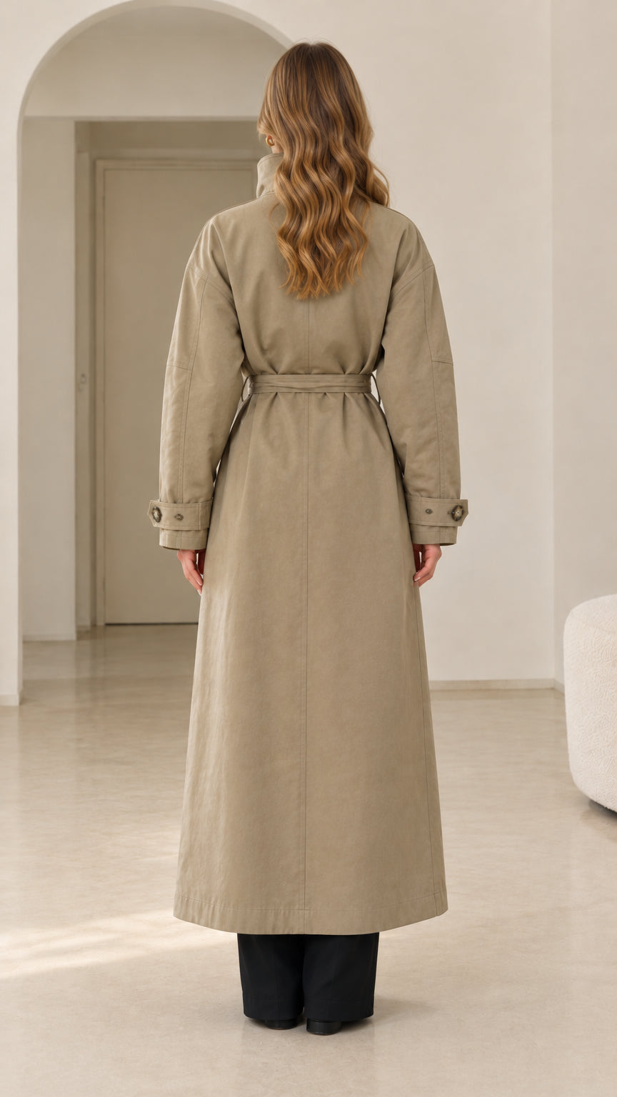 Back view of woman wearing khaki maxi trench coat with tie belt