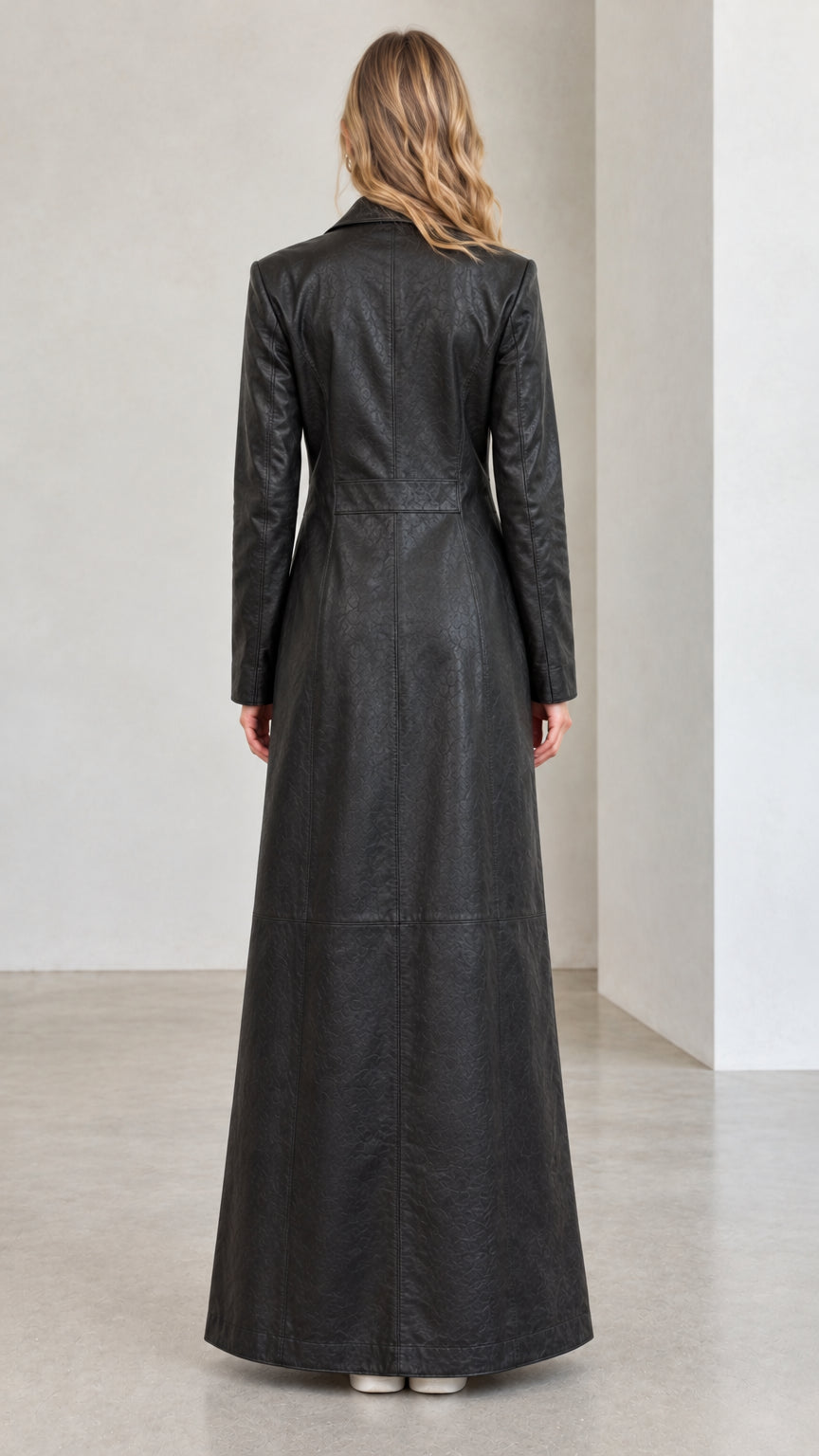 Back full view of woman wearing full-length black faux leather trench coat