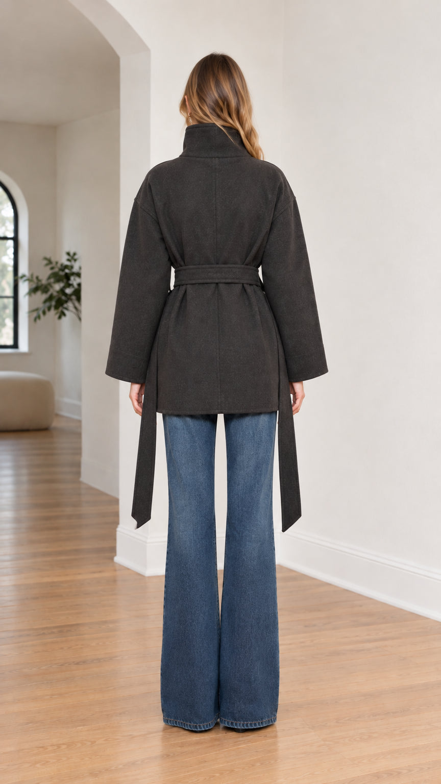 Back view of model in charcoal belted coat showcasing clean silhouette and length