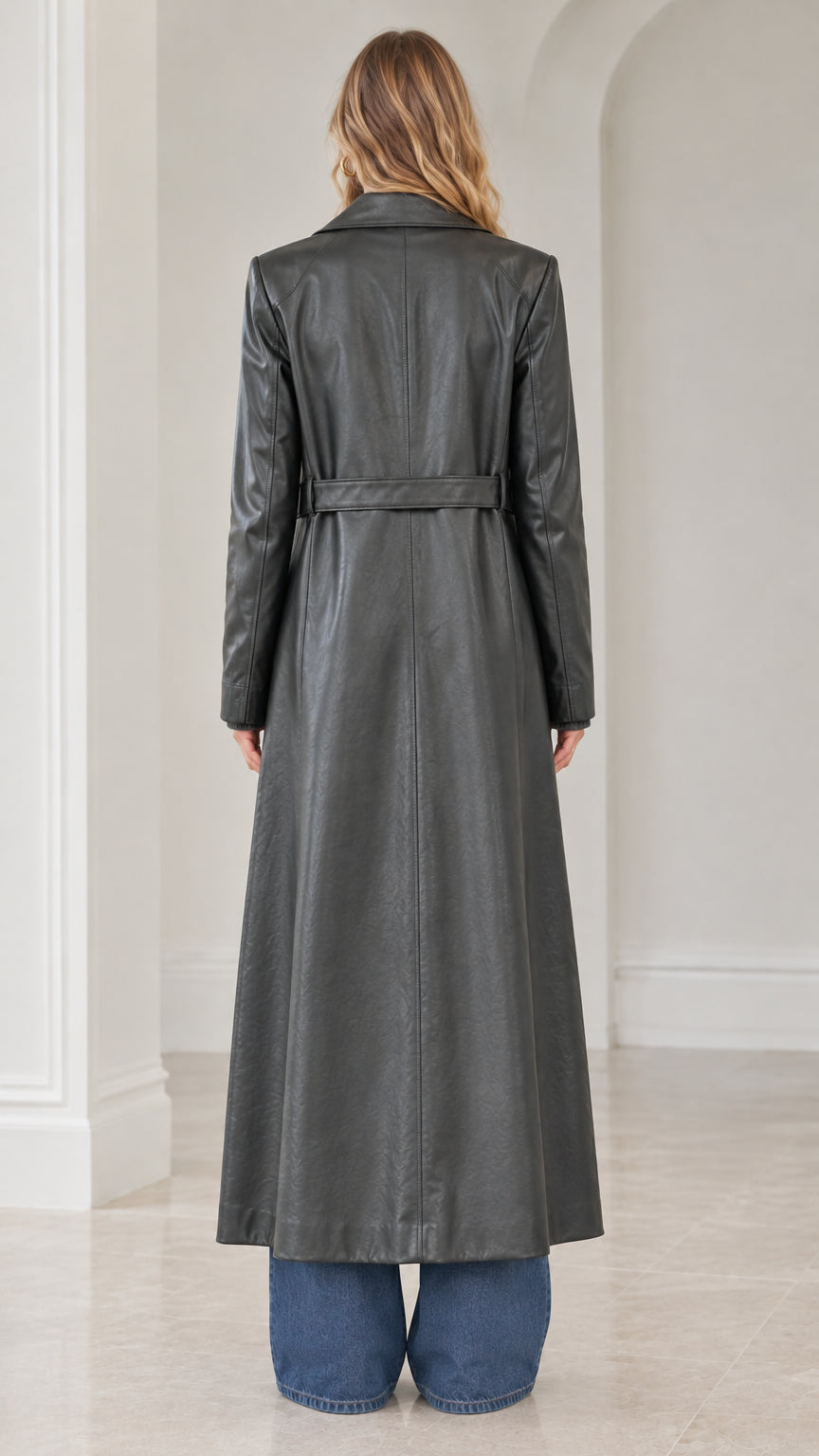 Rear view of model wearing charcoal grey faux leather trench coat featuring back waist band detail