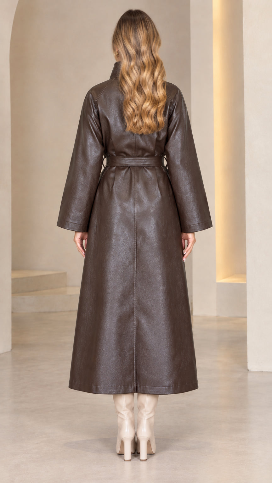 Back view of model wearing dark brown belted faux leather maxi trench coat
