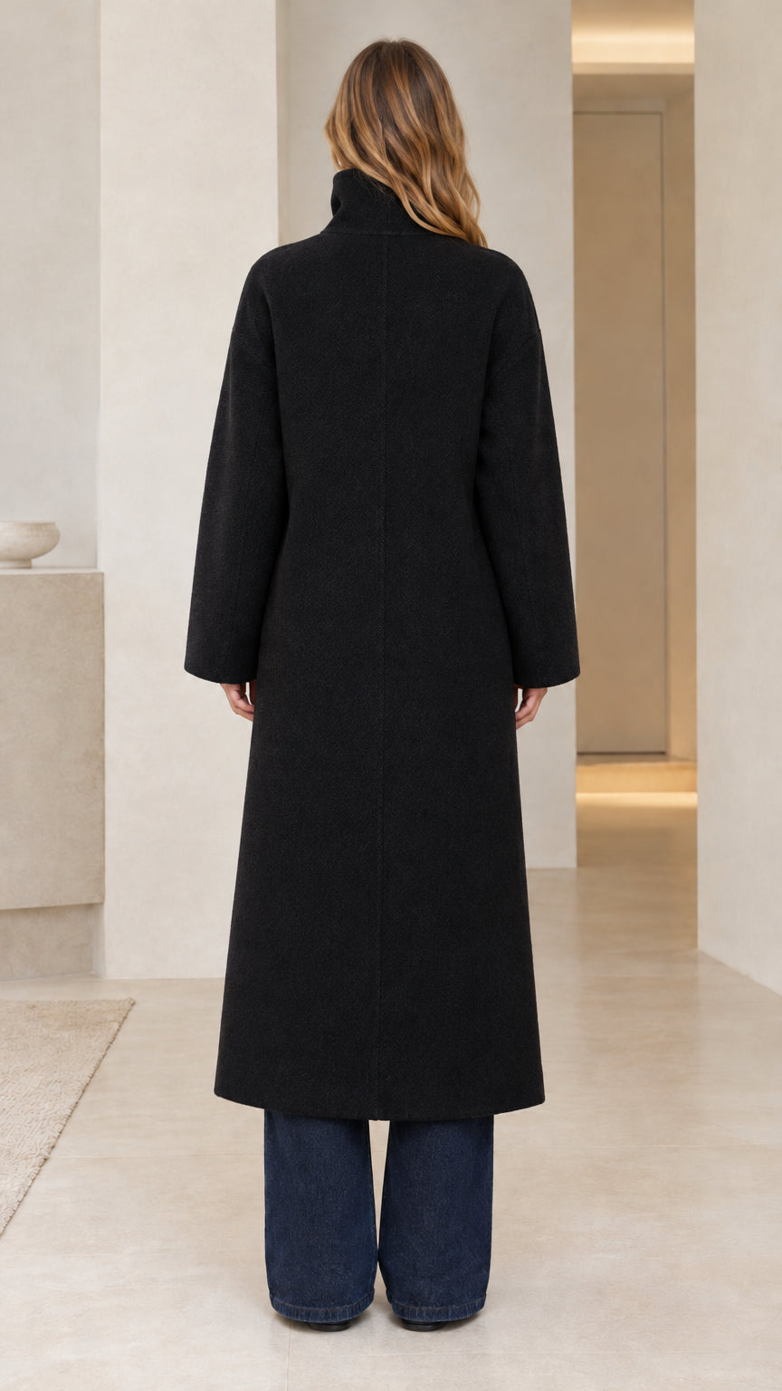 Back view of model wearing minimalist black full-length stand collar overcoat