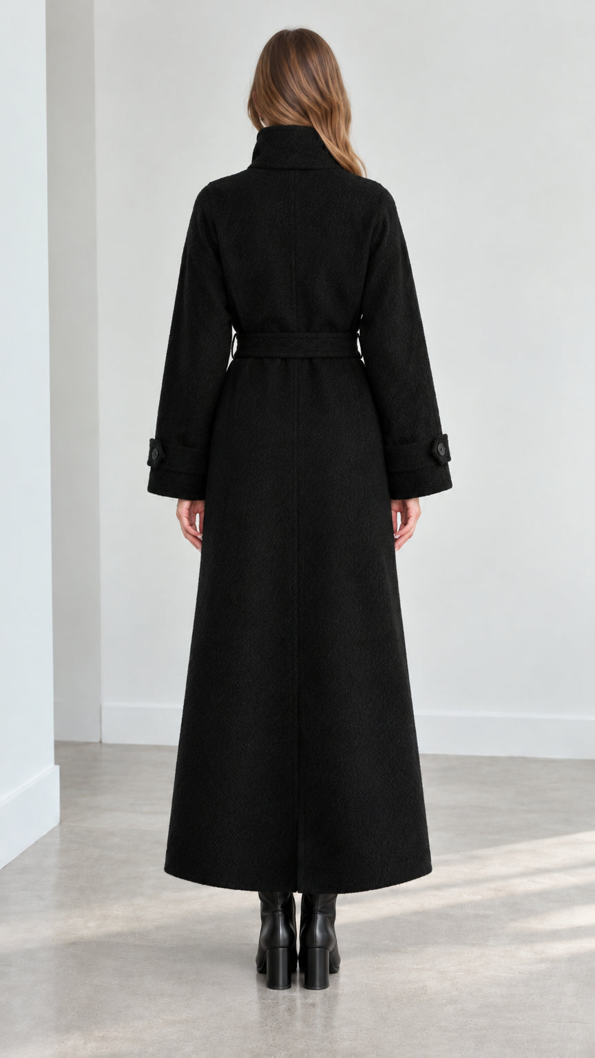 Back view of model wearing black long maxi coat with tie belt