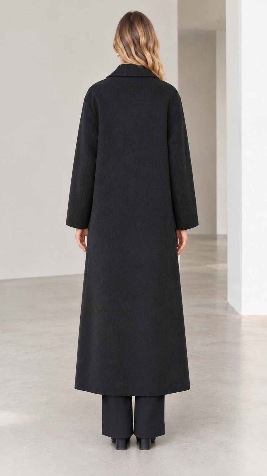 Back view of woman wearing black longline overcoat with center hem slit