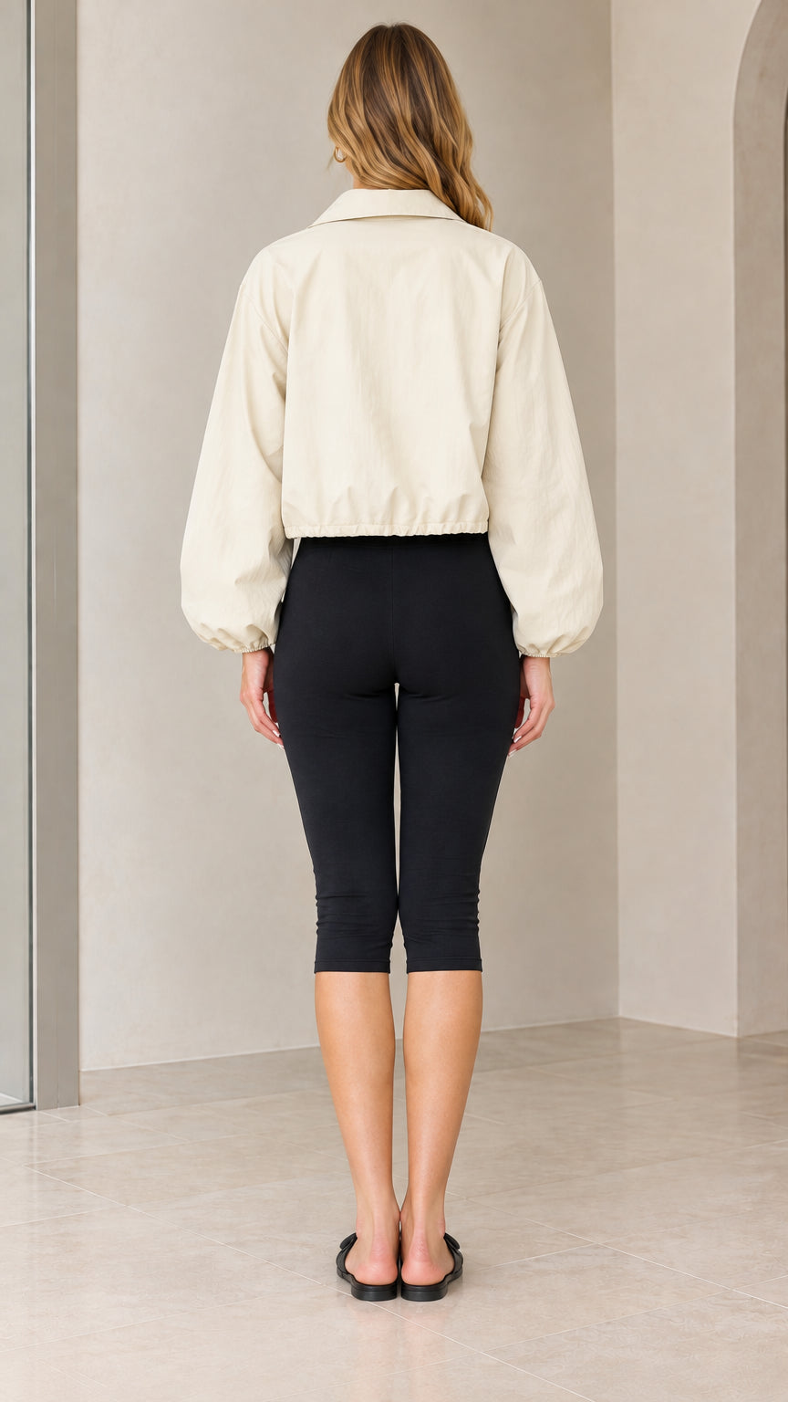 Back full-length view of model wearing beige cropped zip-up jacket with elastic hem