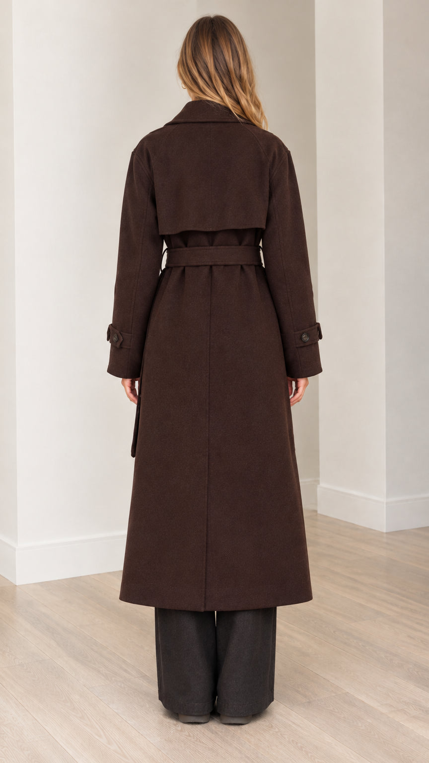 Back view of woman wearing brown longline overcoat showing storm flap and belt