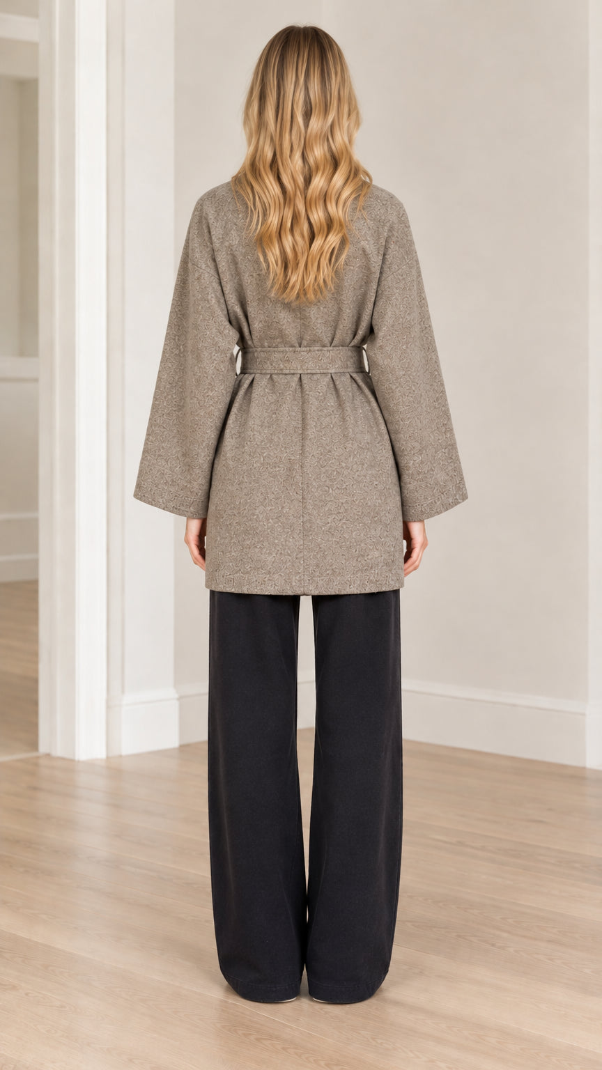 Back view of model wearing taupe textured wrap coat with tied waist sash