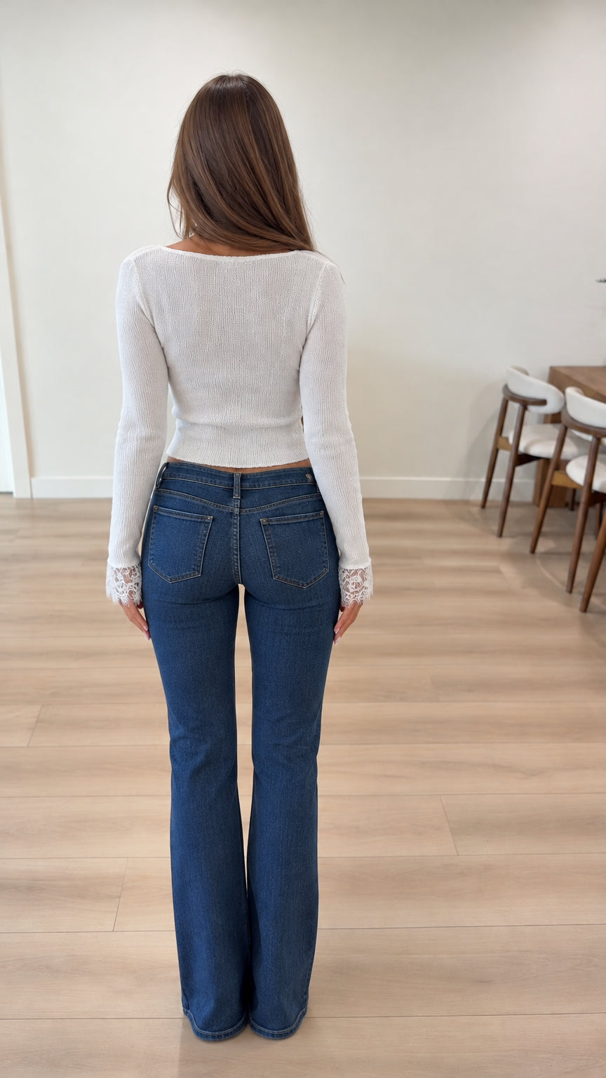 Back view of woman wearing white long sleeve lace trim knit cardigan with flare jeans