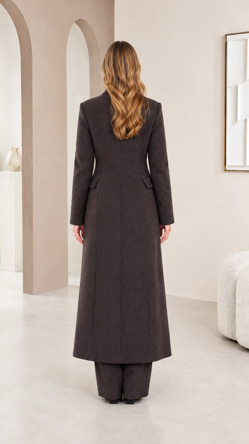 Back view of model showing tailored fit and longline hem of charcoal coat