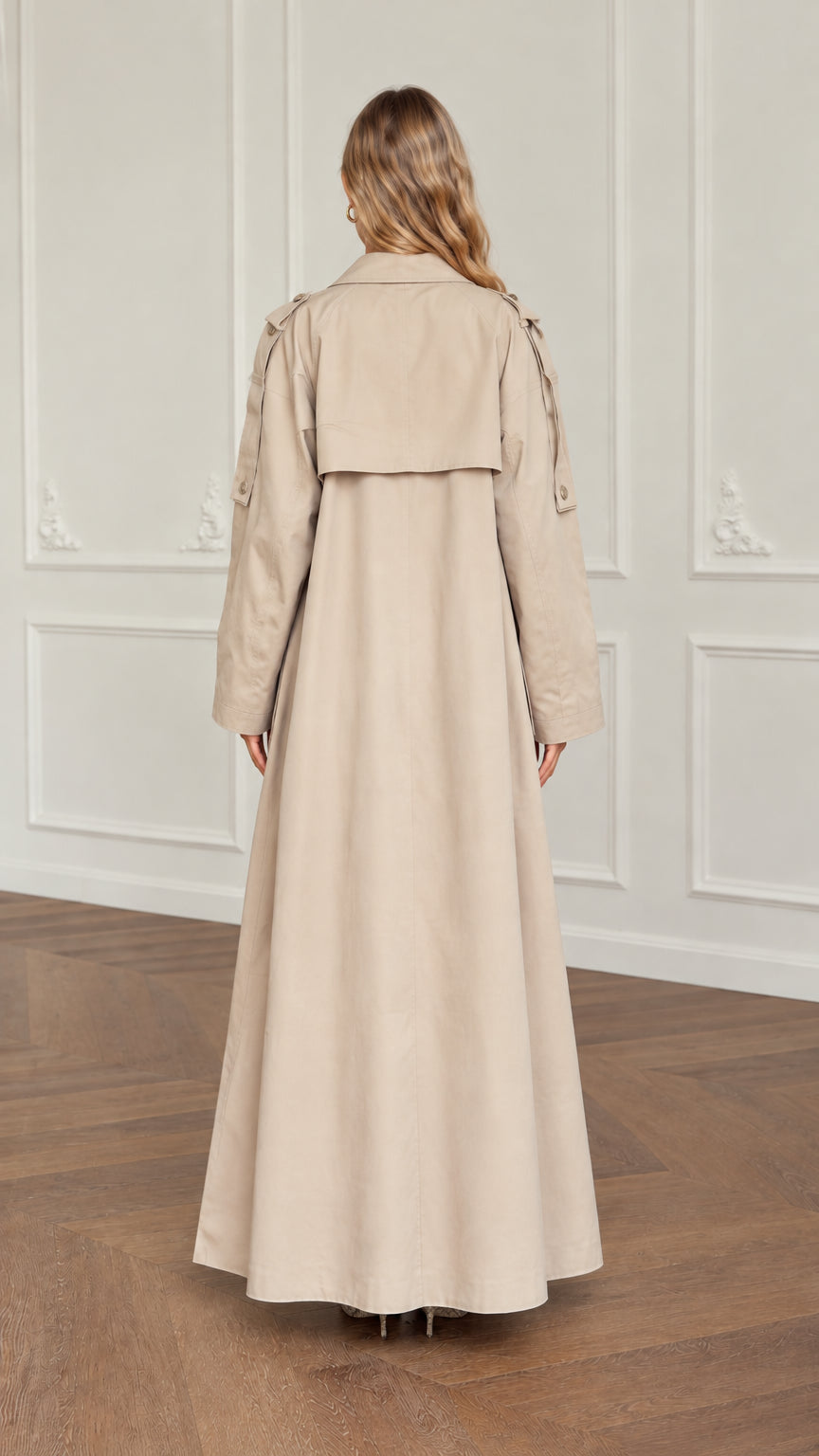 Back view of woman wearing beige maxi trench coat showing back flap detail